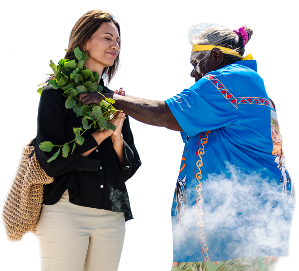 An indigenous woman in traditional clothing blessing a younger woman with a plant during a welcome to country ceremony in Kimberley, Australia.