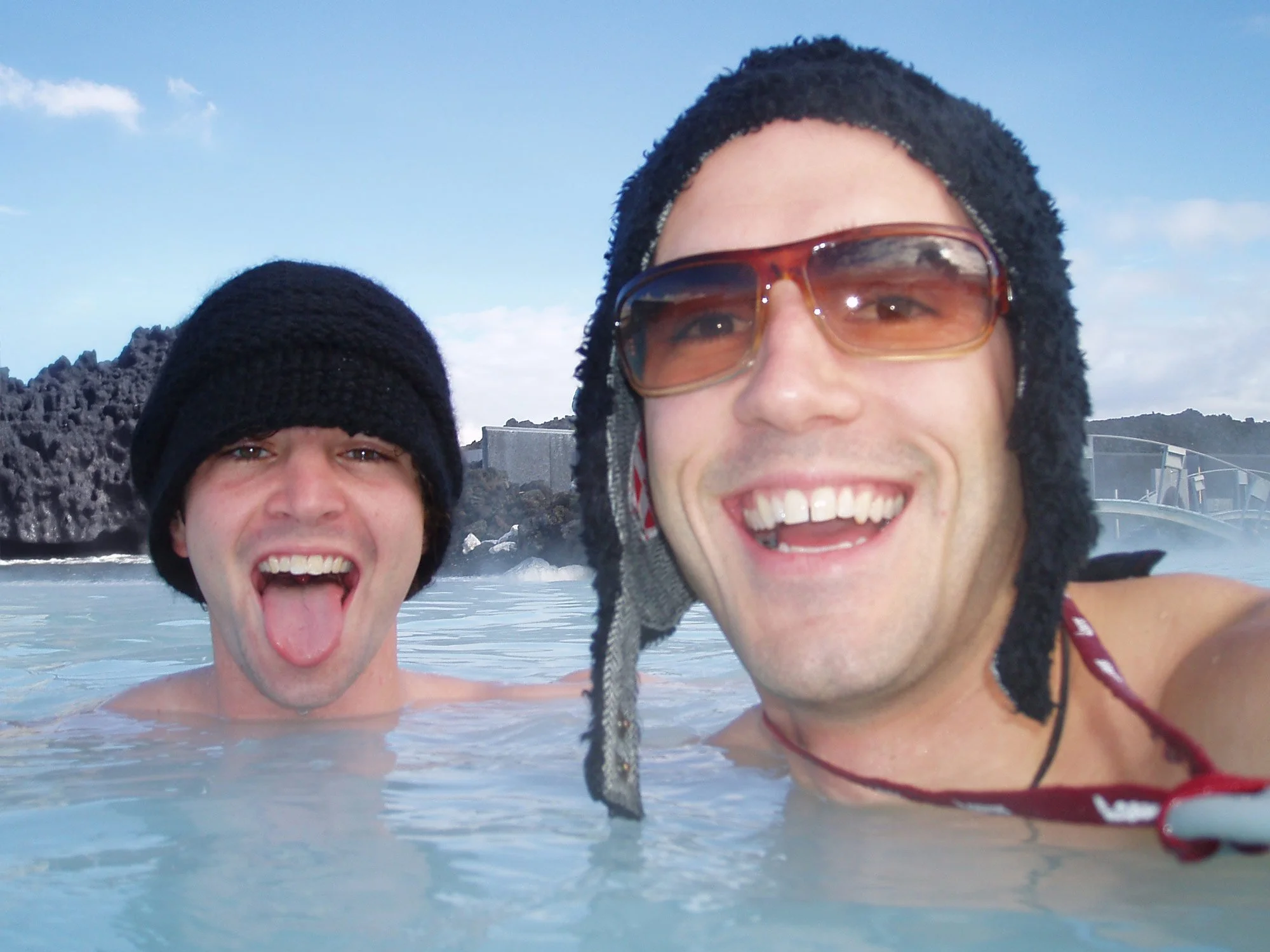 WABU Creative founders Scott David Martin & Marc Dionne in a hot spring, smiling and wearing winter hats and sunglasses, at the Blue Lagoon in Iceland.