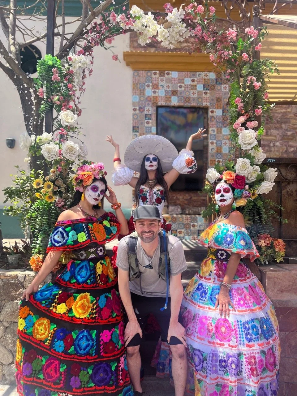 Behind the Scenes of WABU Creative. Director Scott David Martin with women in traditional Mexican dress. Colorful embroidered and floral patterns with sugar skull face paint, typical of Día de los Muertos celebrations. 