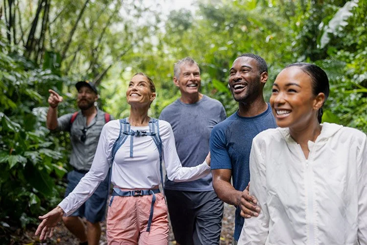 Five people hiking in a lush forest in the Caribbean, smiling and enjoying the outdoors.