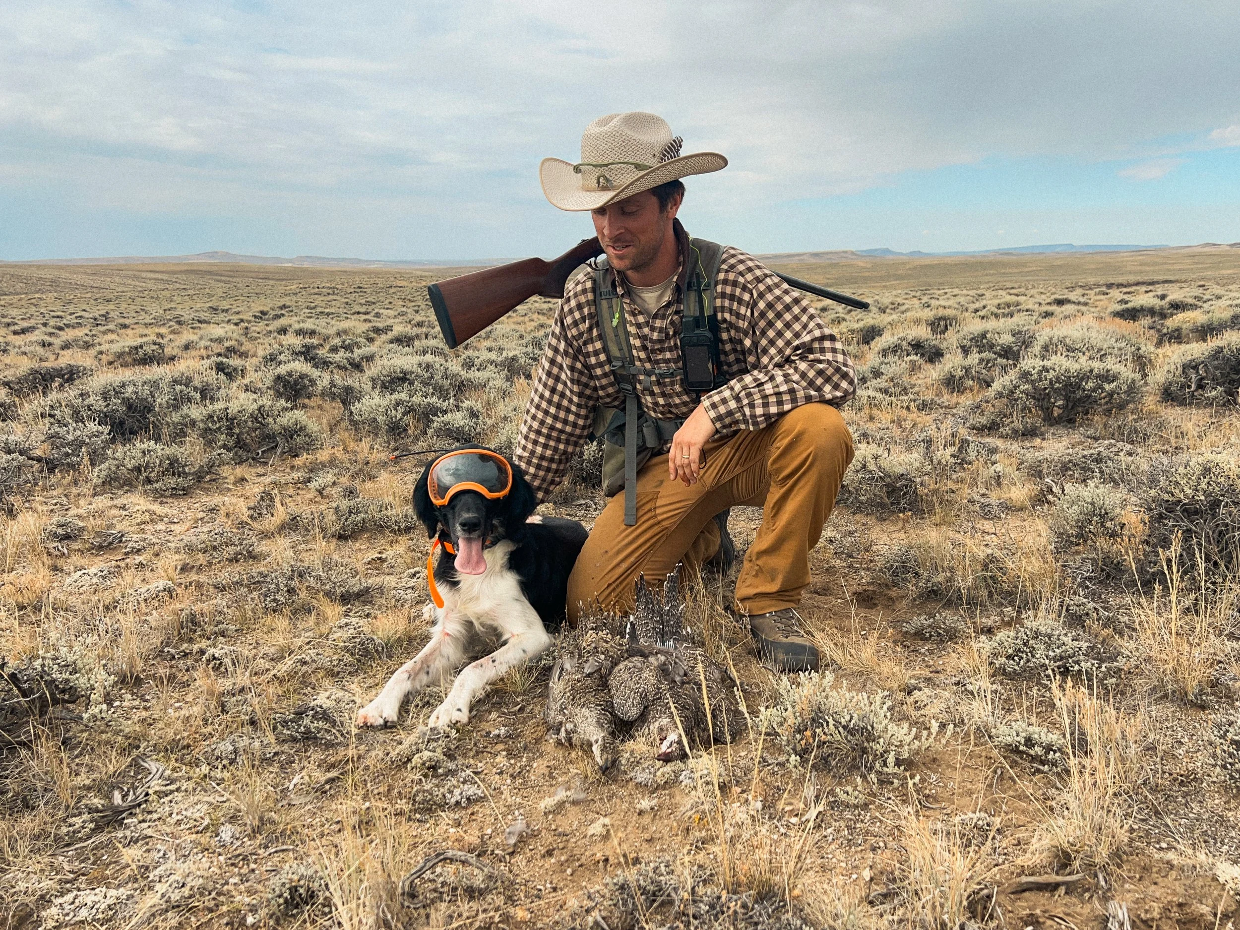 A man and his dog, a Large Munsterlander, posing with two Sage grouse from Southeast Wyoming.