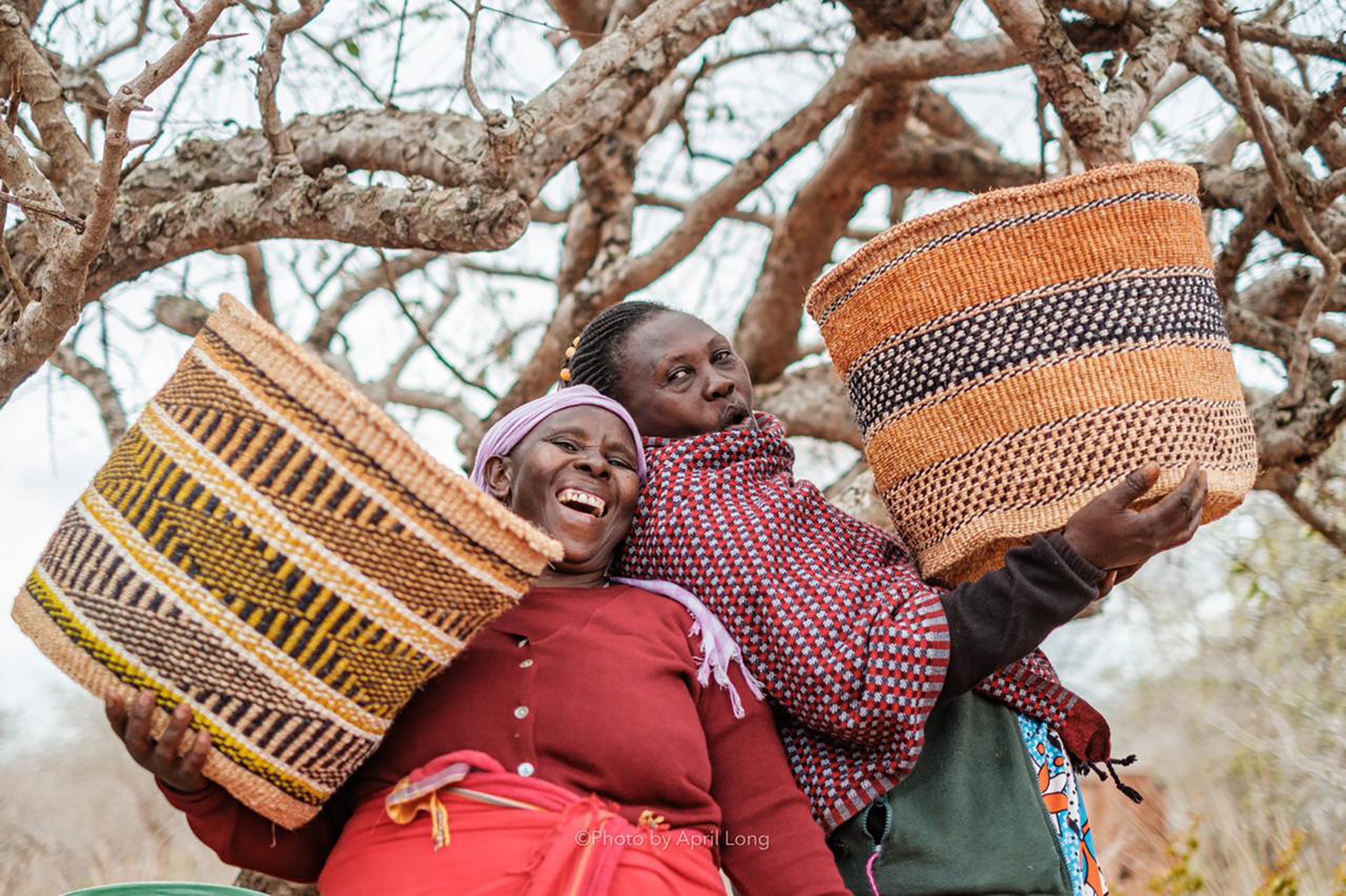 Nest HadithiCrafts smiling together with woven baskets.