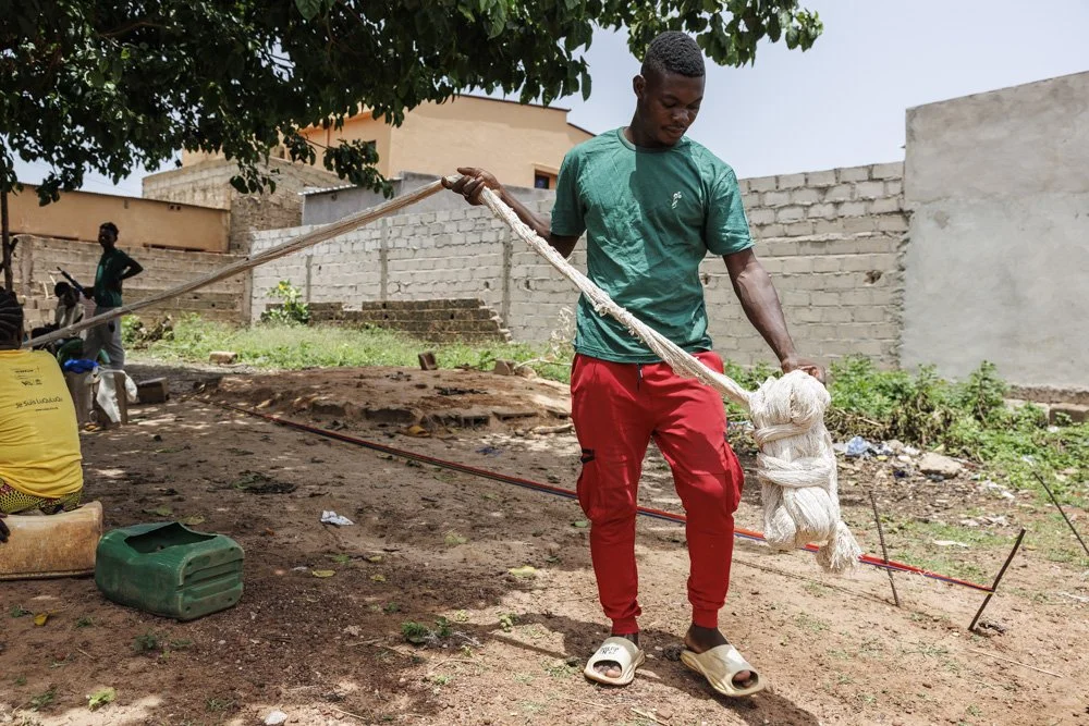 Bihoun Honoré, a weaver in Bobo Dioulasso, Burkina Faso, carries freshly spun yarn for weaving. Originally from Boundoukui, he was displaced by a terrorist attack and now weaves alongside four other displaced men.