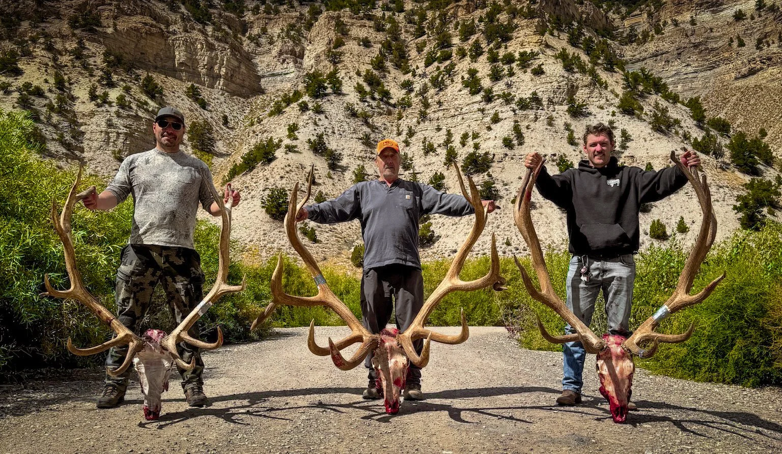 Hunters posing with a trophy bull elk after a successful guided elk hunt in Utah with SD Outfitters.
