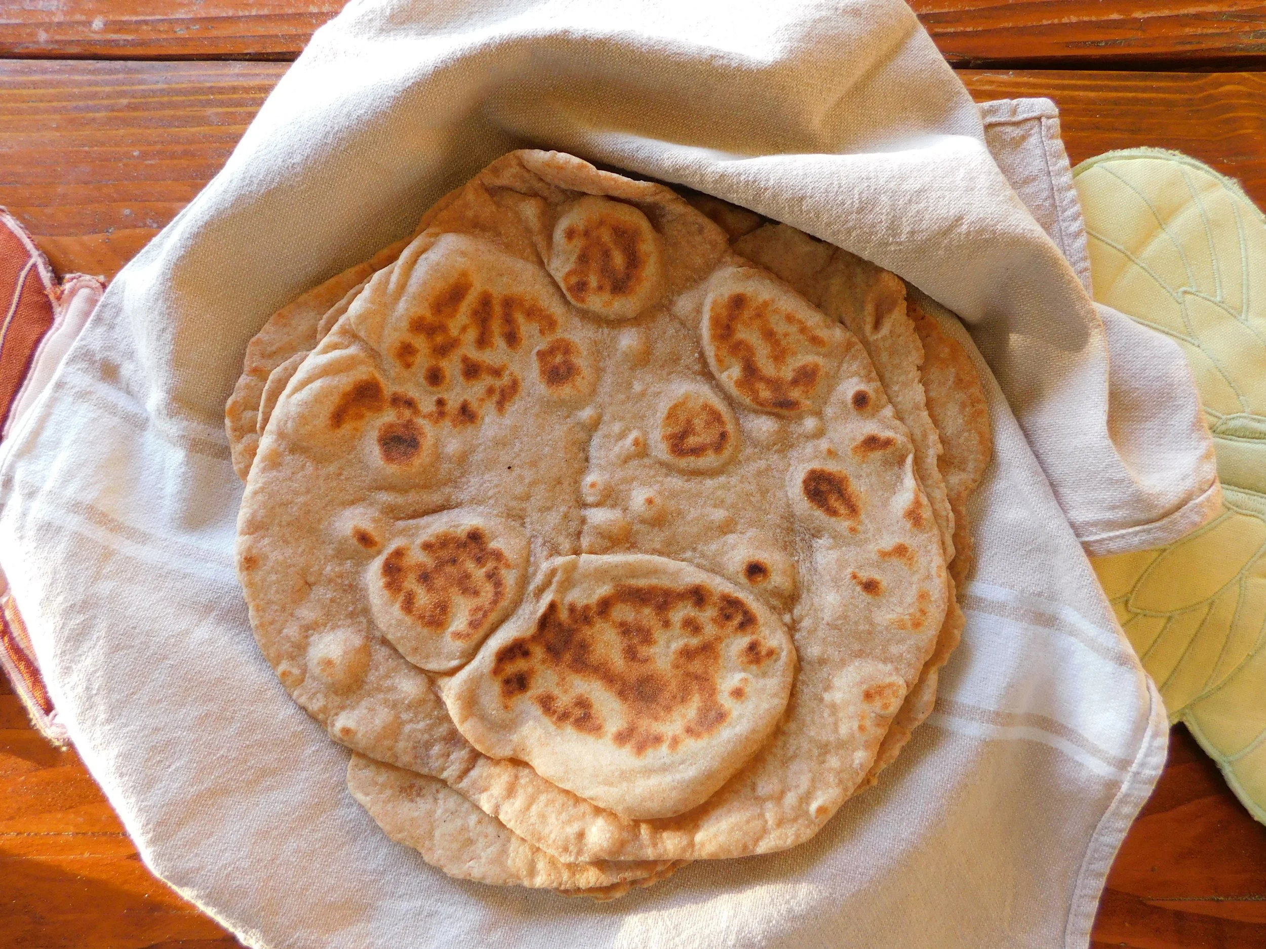 Stacked whole wheat tortillas fresh from the griddle wrapped in a towel