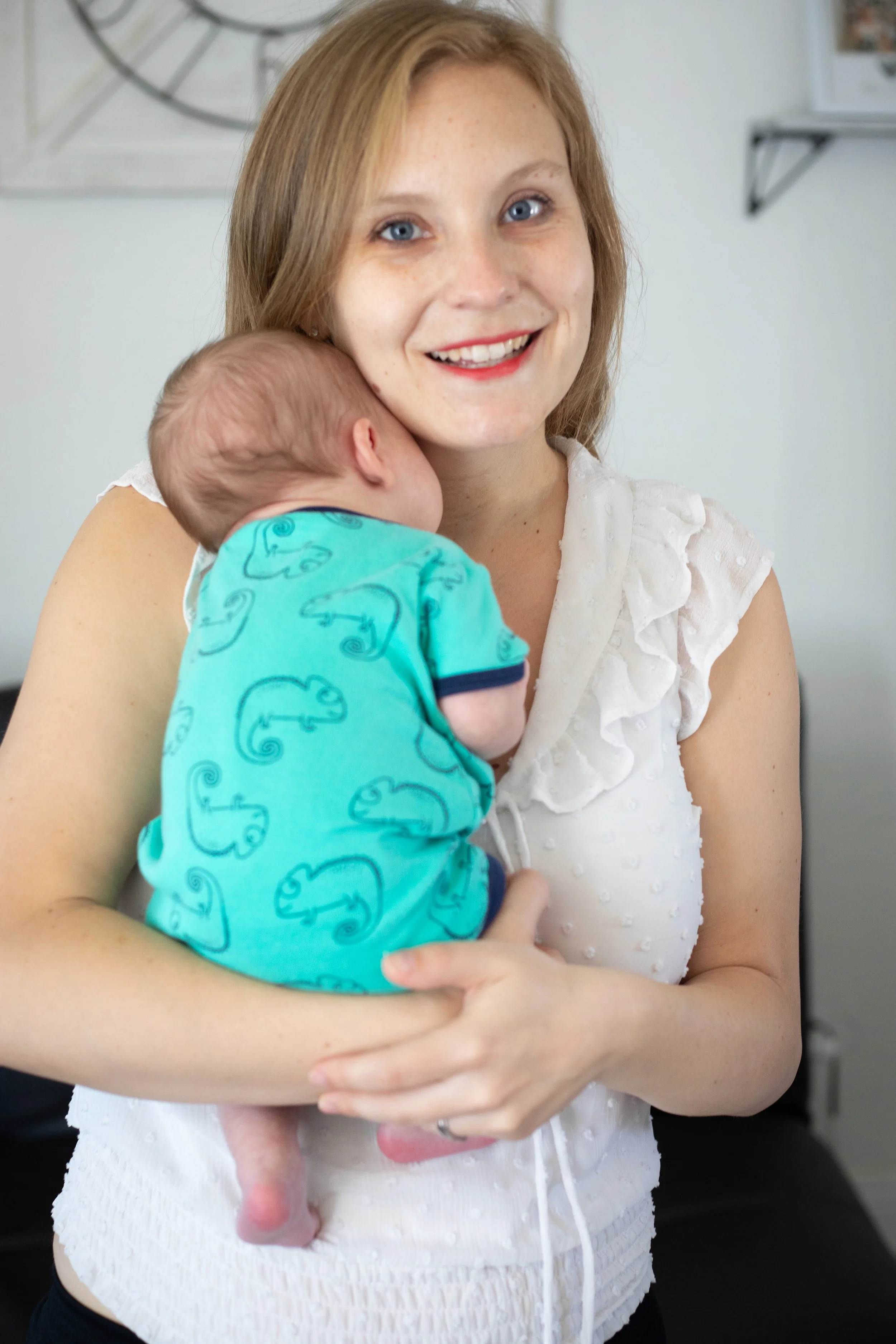 Mom holding her newborn baby wearing a white top with a pop of color. High deset family photography session.