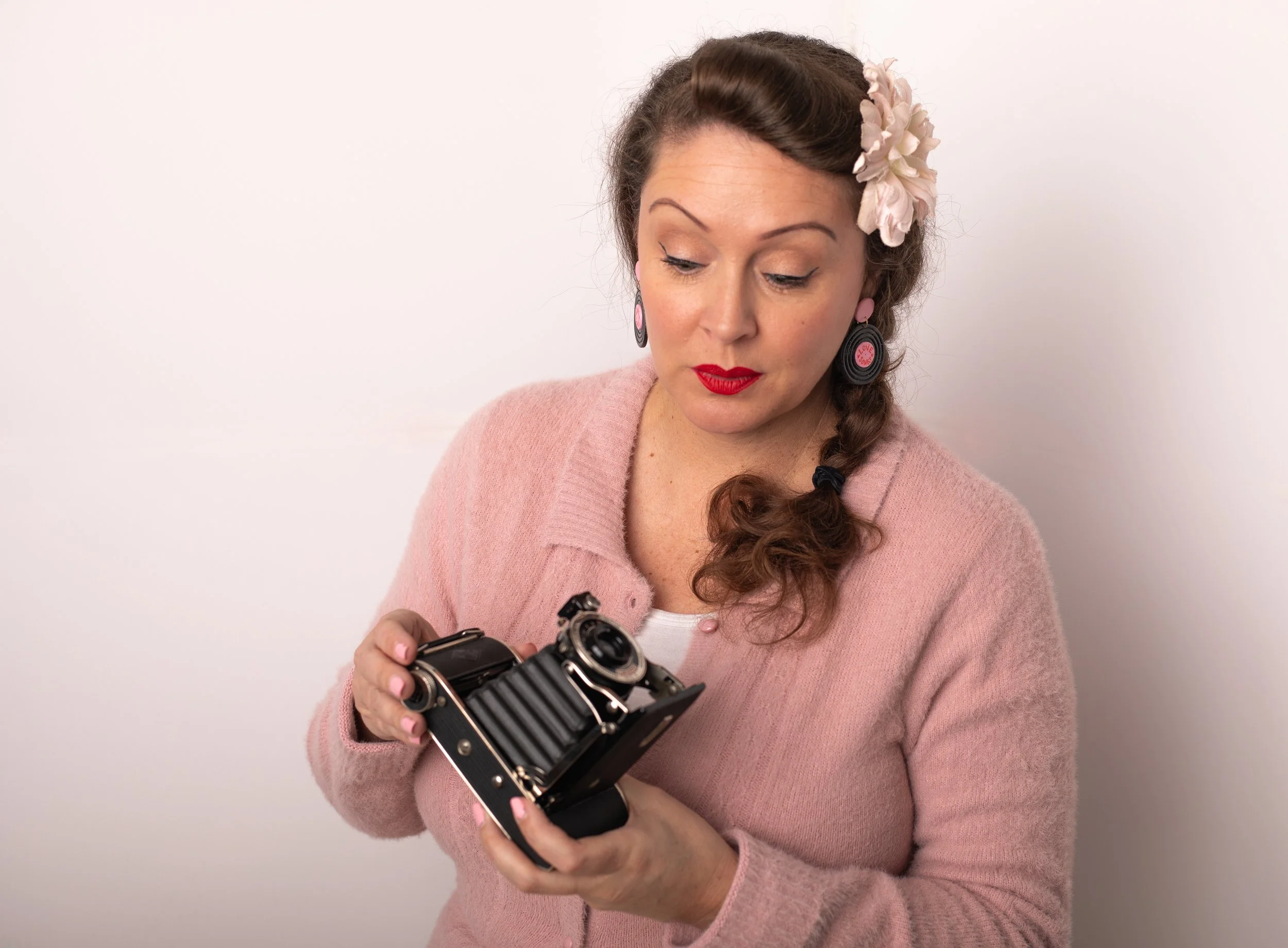 Woman in pink admiring vintage camera for branding photoshoot. Pinon hills family photographer.