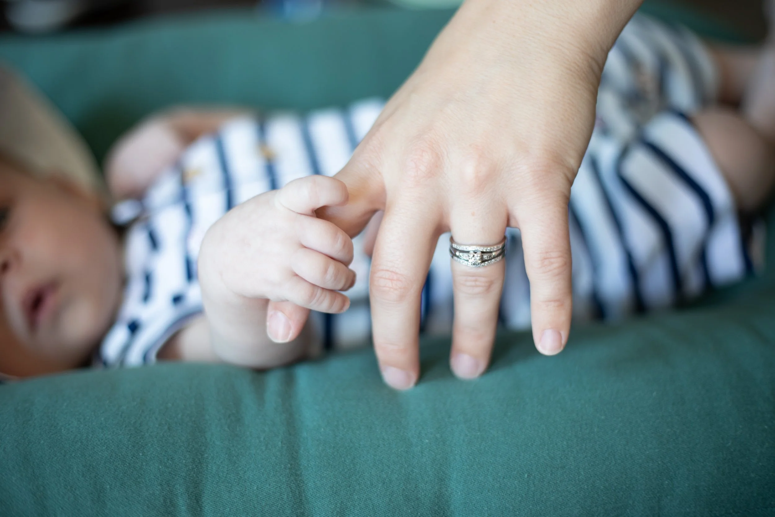 Newborn holding mom finger in wrightwood for family lifestyle in home session by playful photographer.