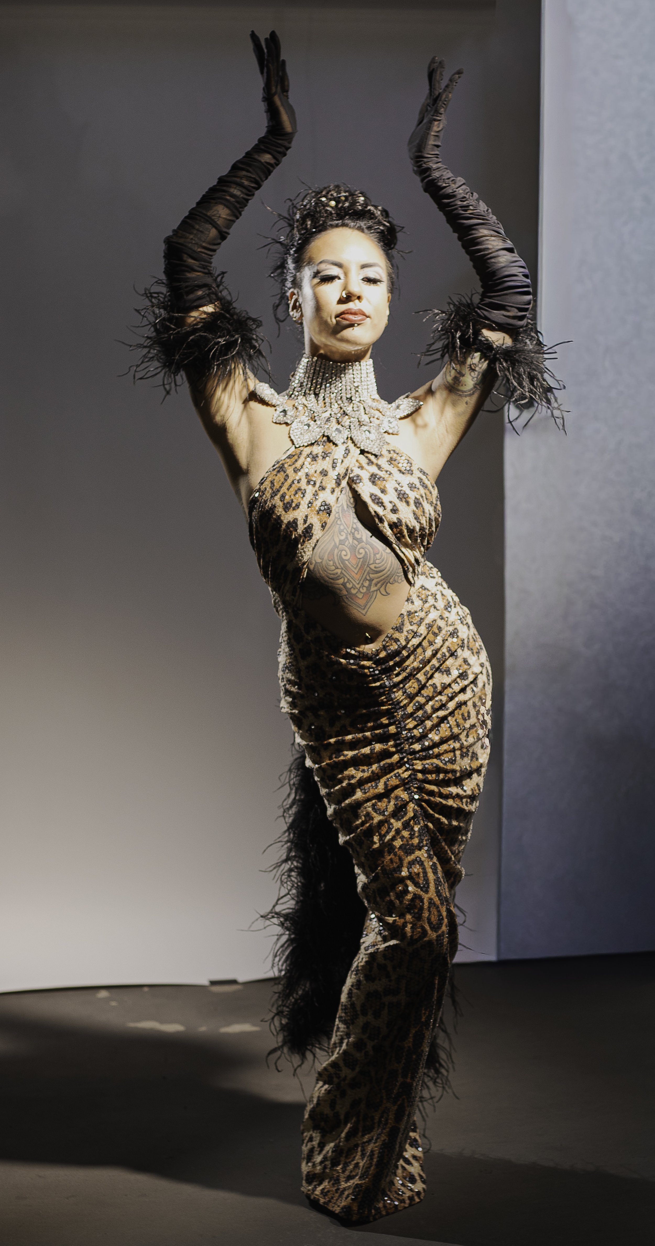 burlesque model woman wearing cheetah gown and feather gloves dancing