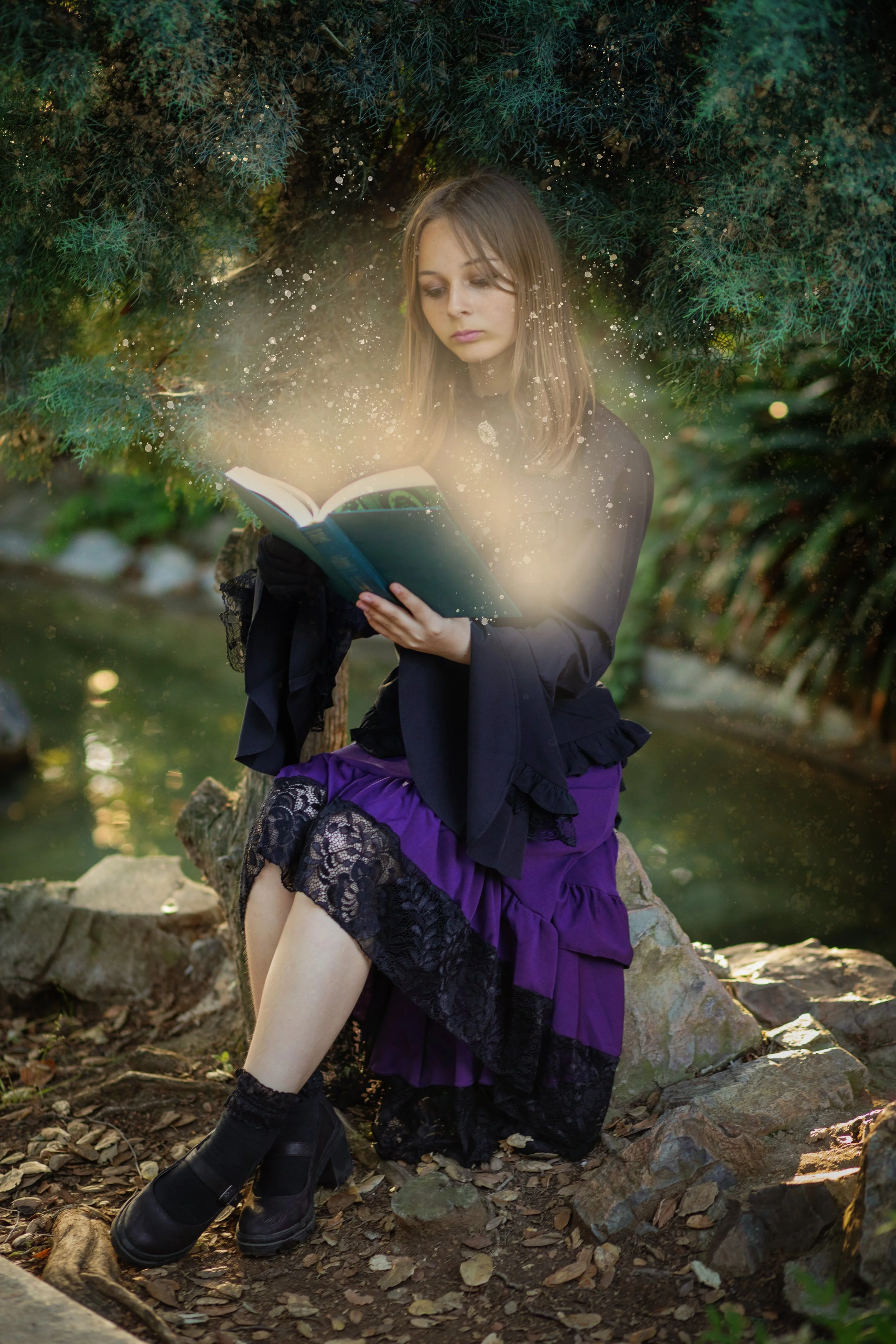 Girl sitting outside, reading book that has light and glitter and magic coming out. Photo by fantasy photographer sharing about craftcation.