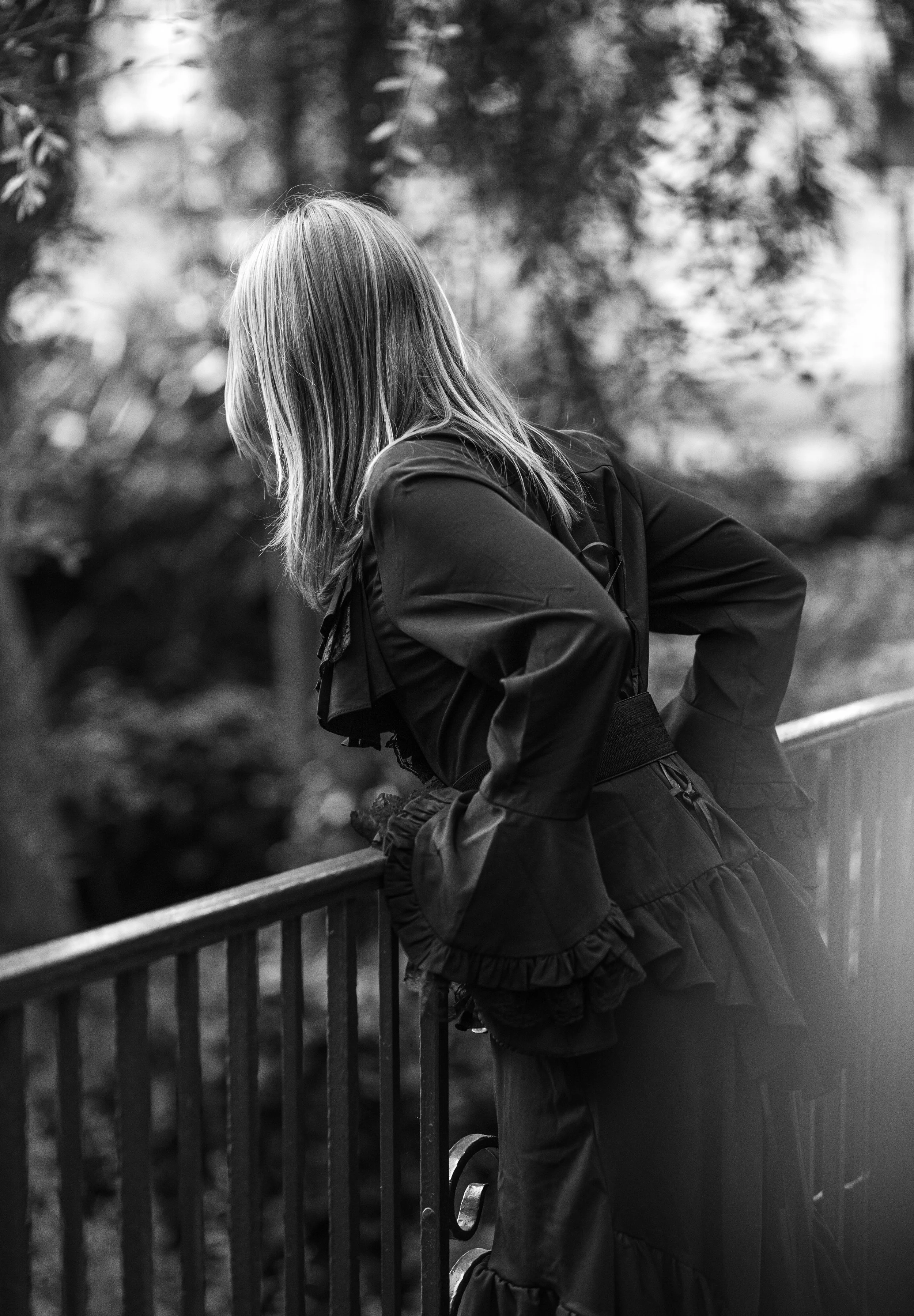 Girl dressed in victorvian clothing leaning over a fence in the forest, by in wrightwood. family photographer.