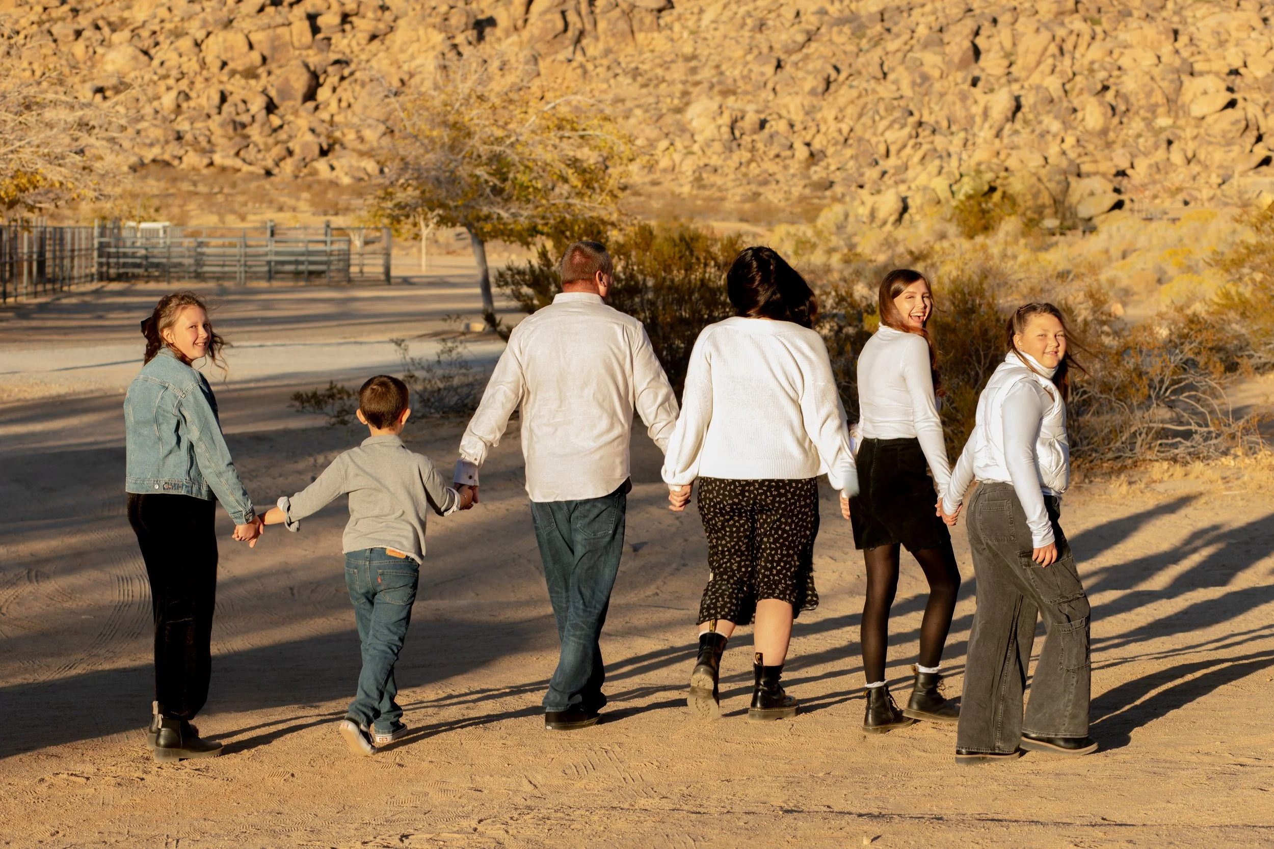 Family photographer in the high desert, large family photo of kids laughing and holding hands, walking away.