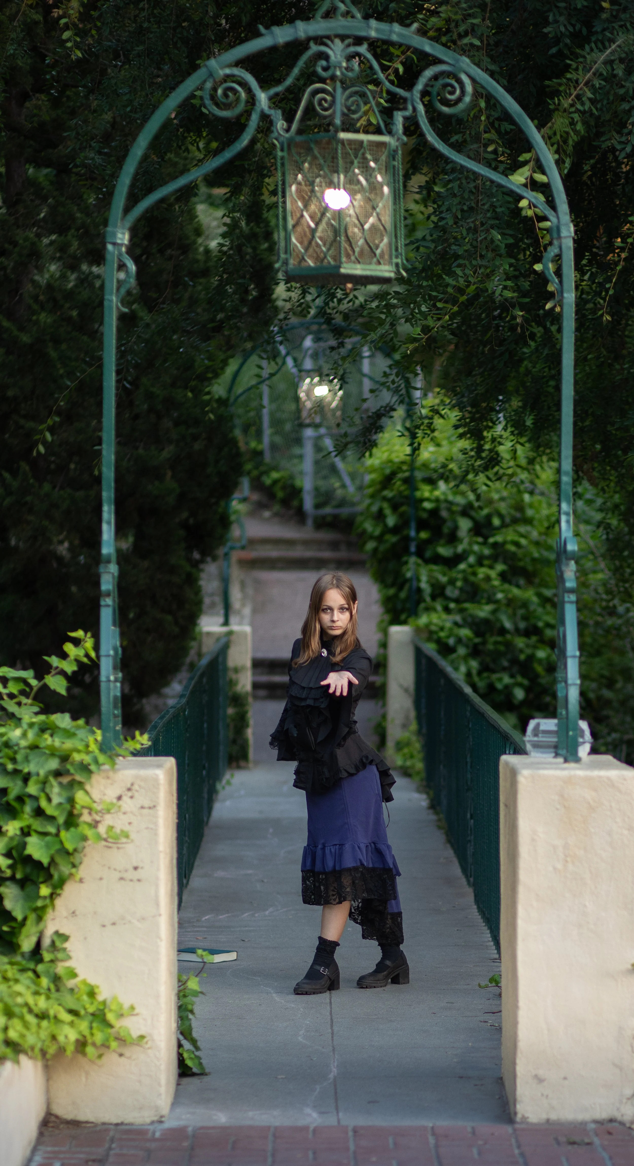 girl standing under lamp, on bridge, inviting you to come with her. Fantasy forest enchantment portraits by inland empire photographer.