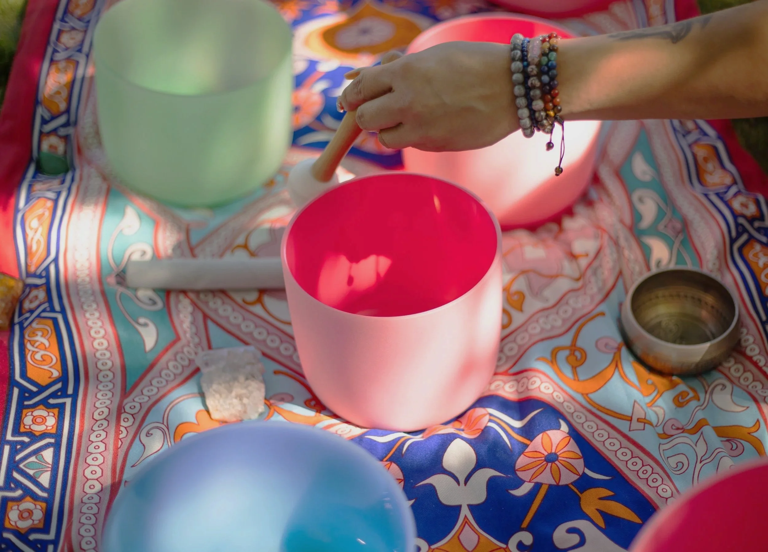 Pinon Hills, CA branding photographer. Close-up of a hand with bracelets reaching into a pink sound healing bowl.