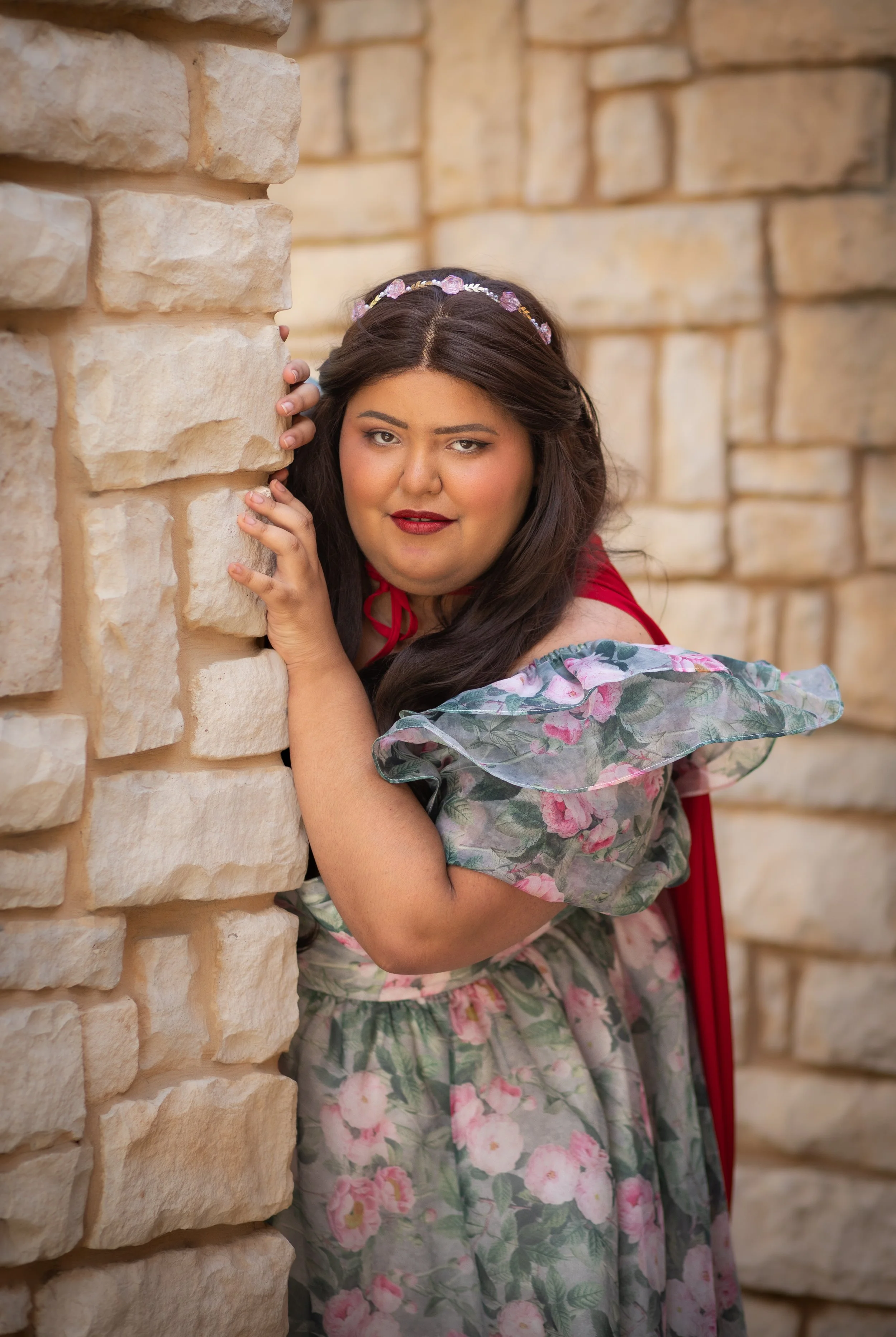 woman dressed as princess with crown and cape hiding behind castle walls. Portrait by fantasy photographer Annette Marie Photography in high desert.