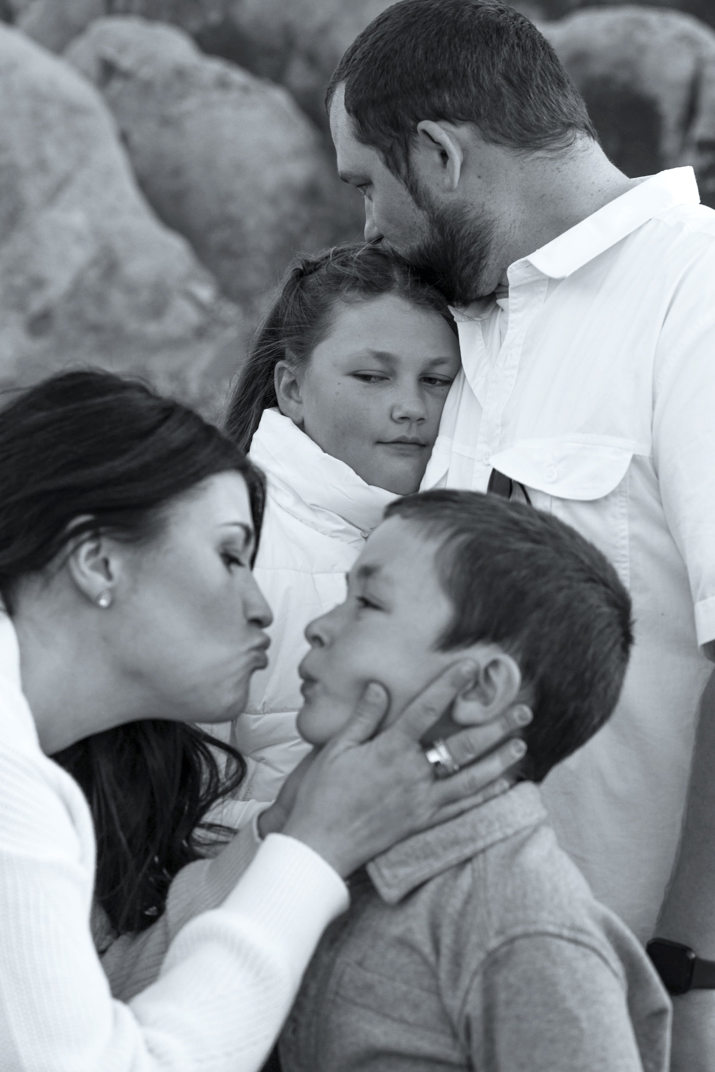 Inland Empire family photos with mom kissing son and dad kissing daughter head.