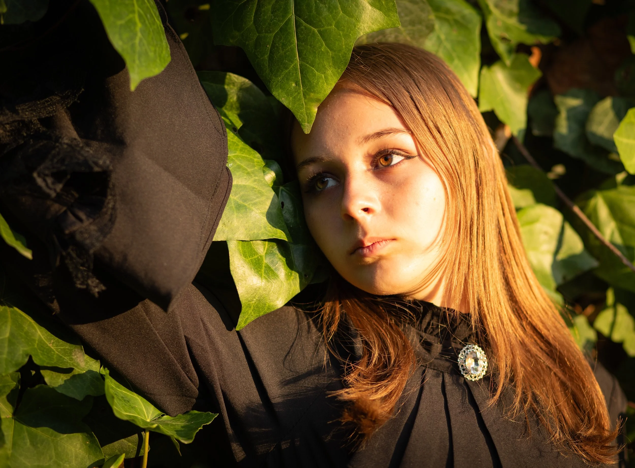 young girl laying in leaves with sun kissing her face