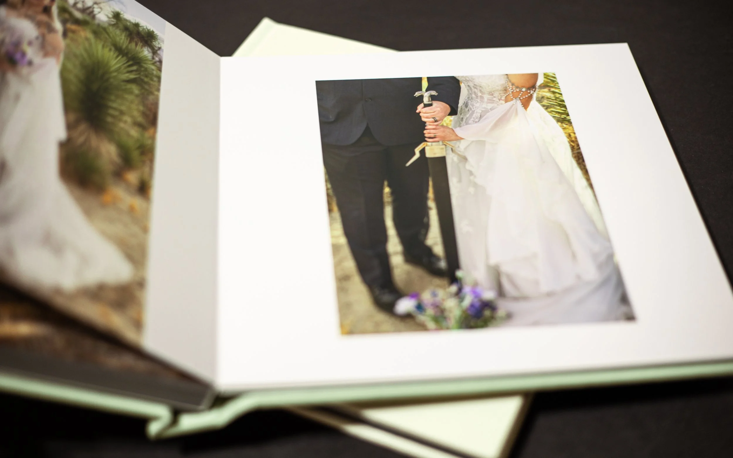 Photo album of fantasy wedding with bride and groom holding sword to show off rings. Fantasy photograper in high desert, ca.