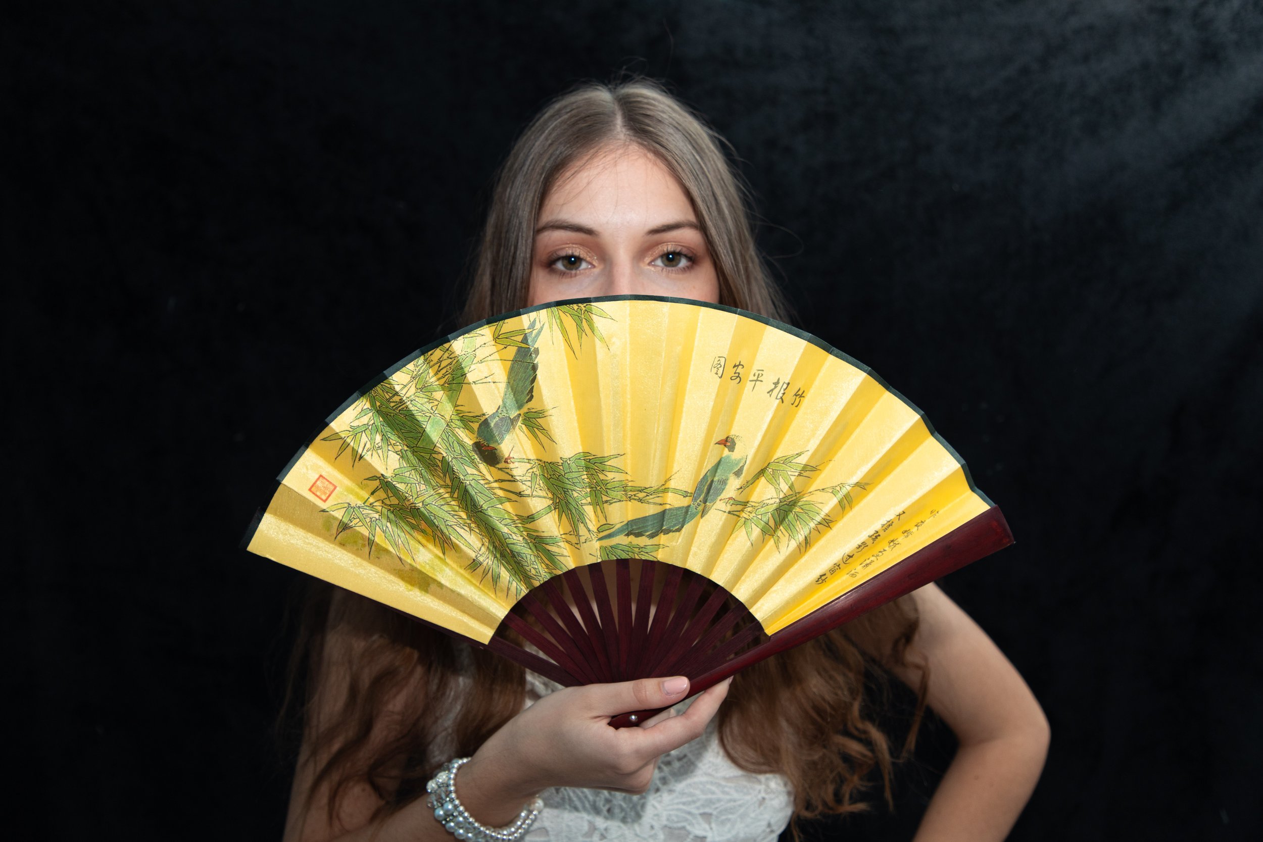Glamourous portraits in Victorville by a playful photographer who makes you feel like a camera isn't even around. Woman holding fan covering face.