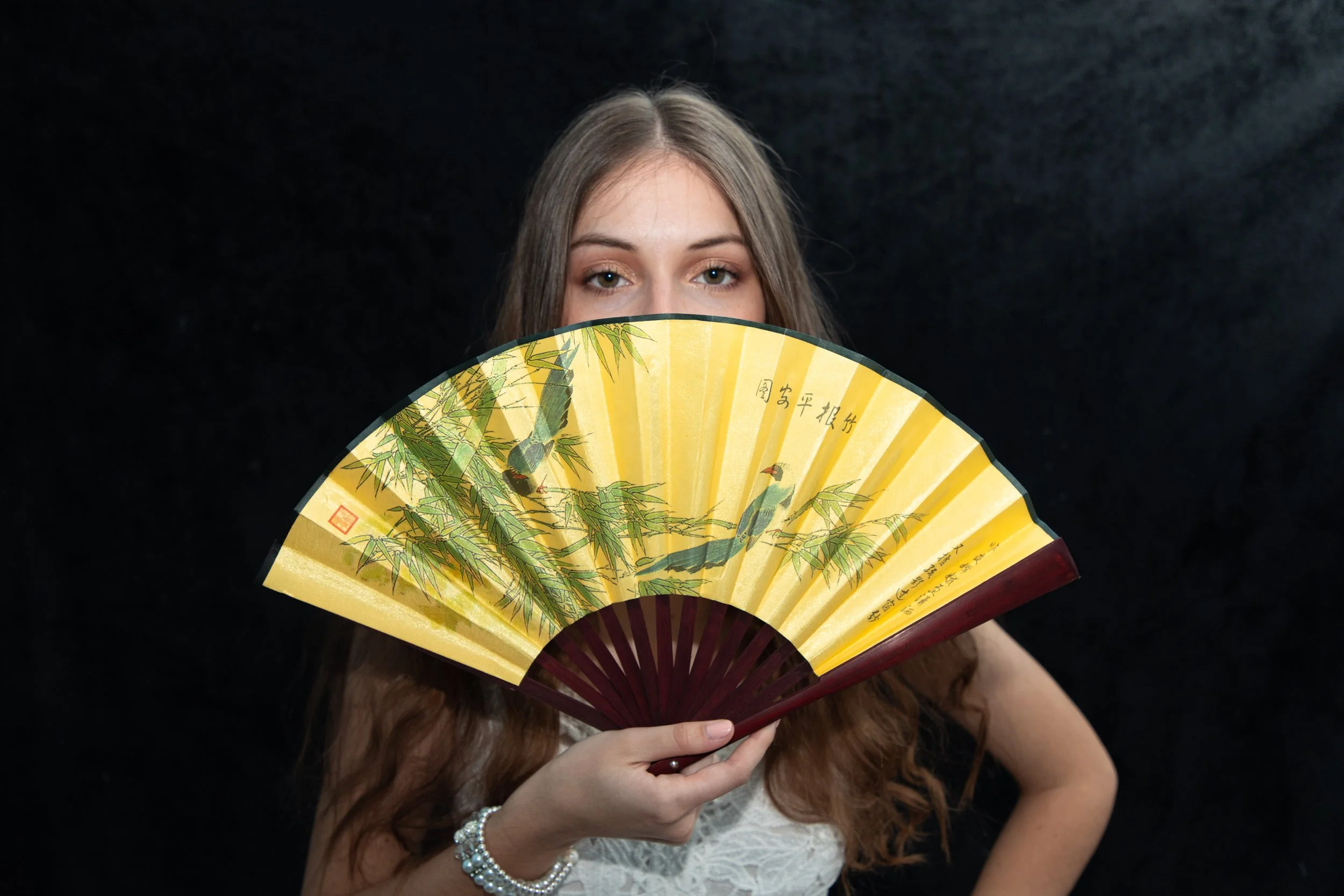 woman holding yellow fan in front of her face by pinon hills photographer.