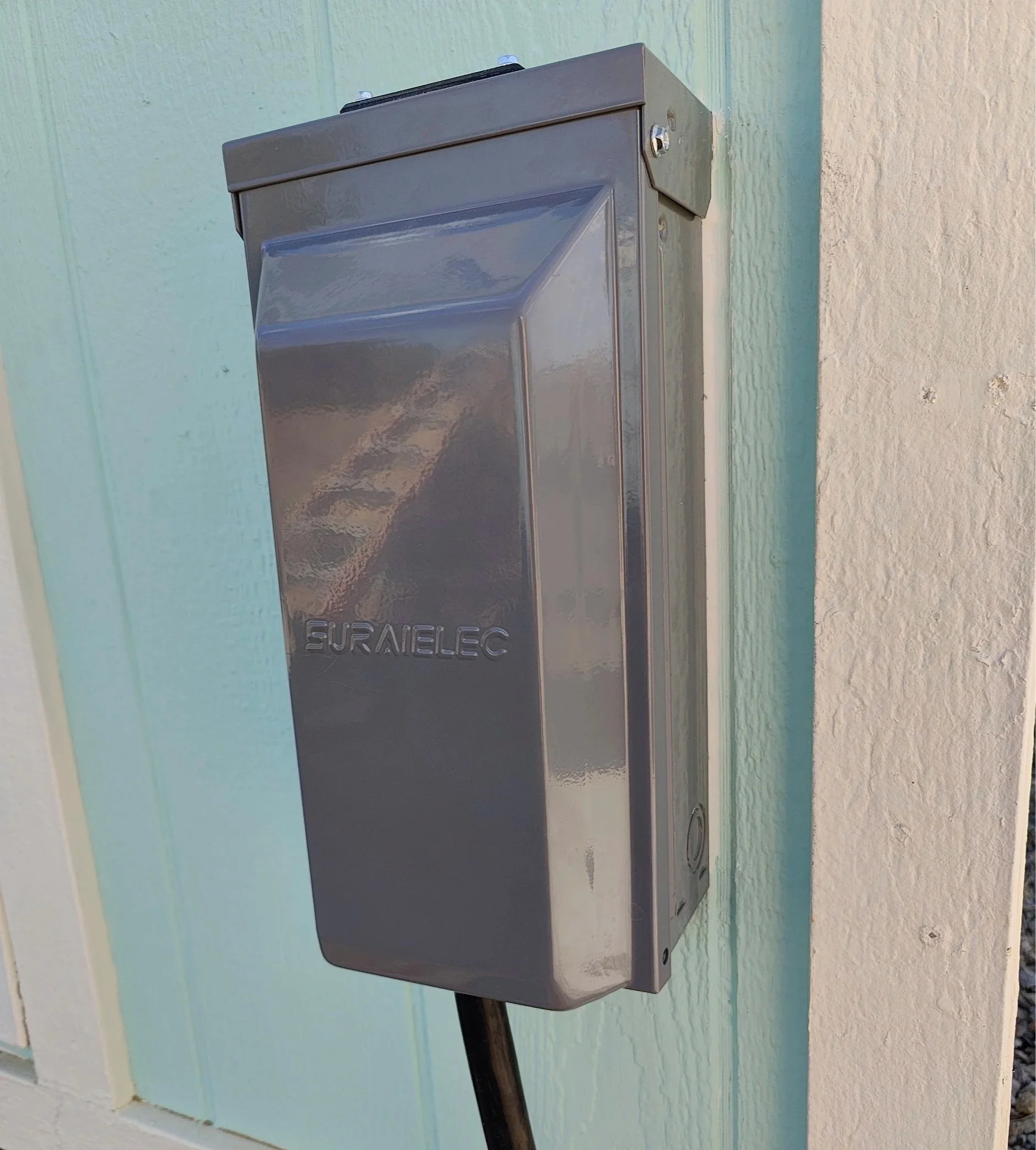 Backyard shed with outdoor electic panel with large plug.