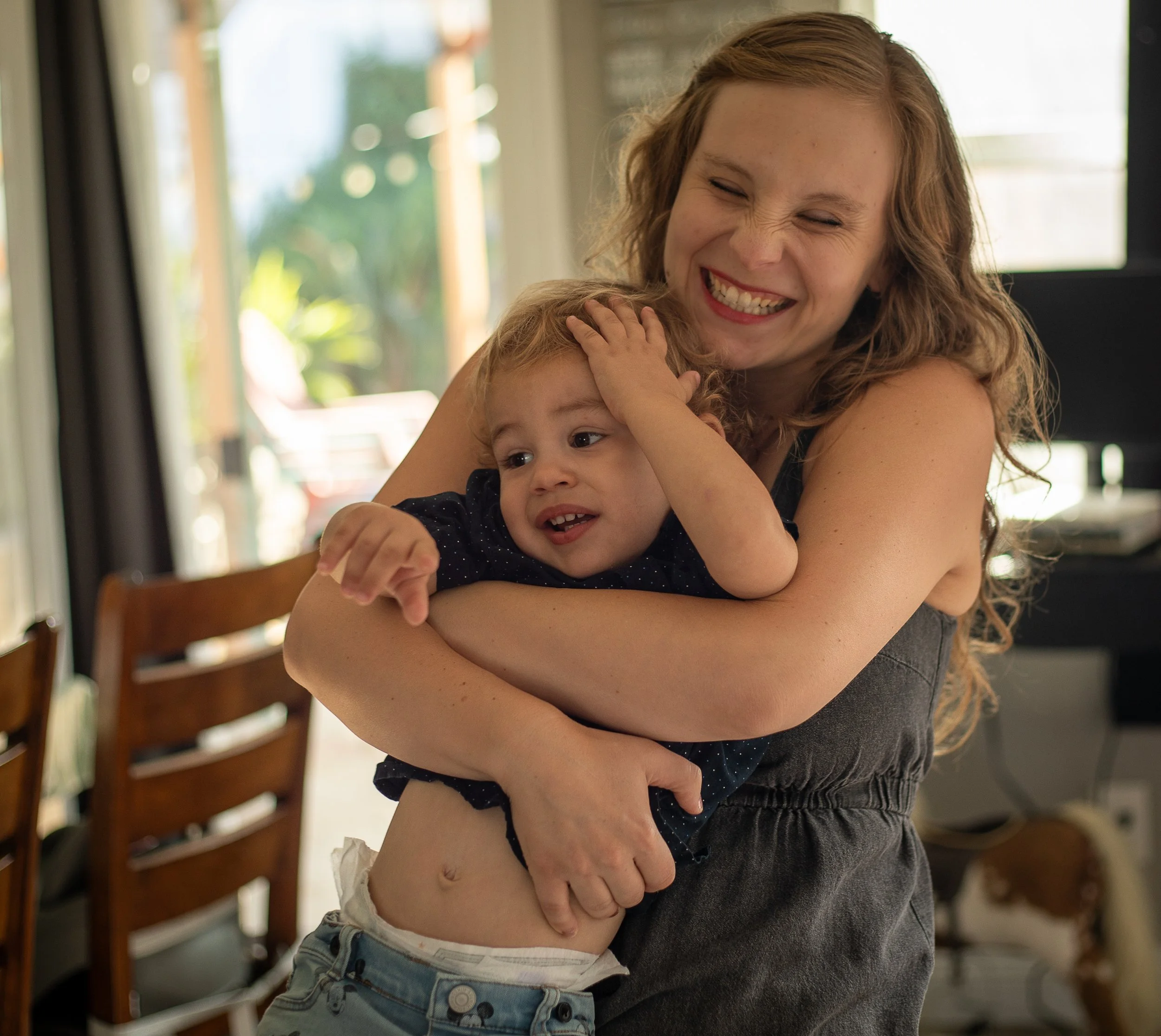 Mom is wrestling a toddler, laughing. A day in the life of motherhood by a lifestyle family photographer in the high desert area.