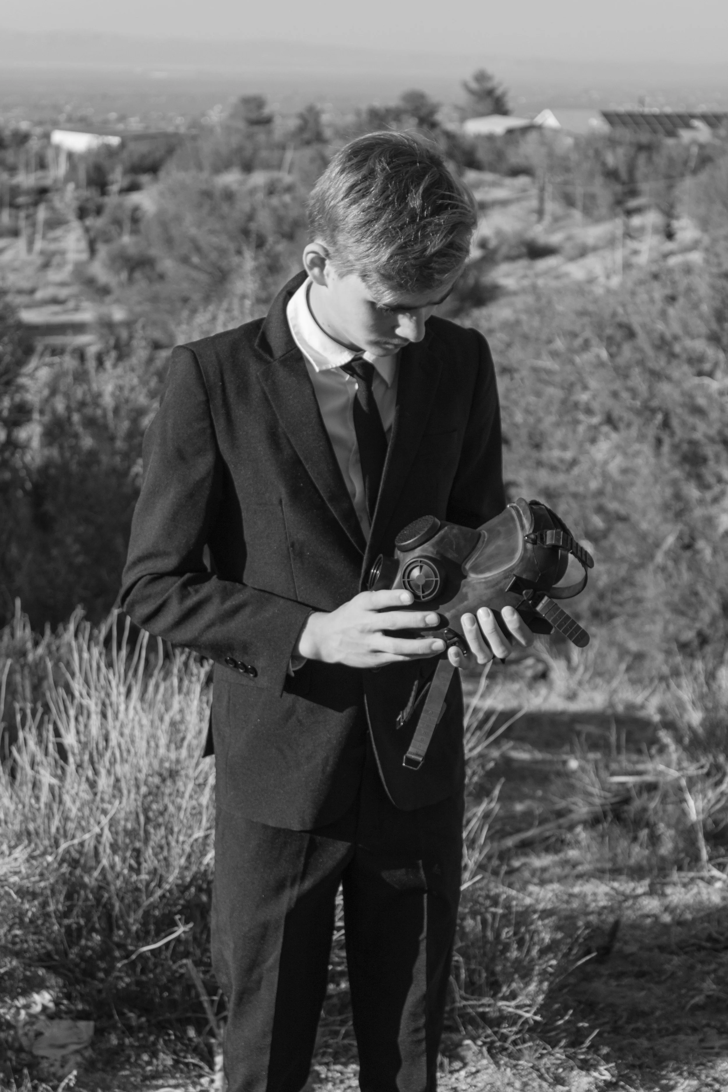 Boy dressed in a suit, holding a gas mask. Surrealism Photos by Southern california fantasy photographer.