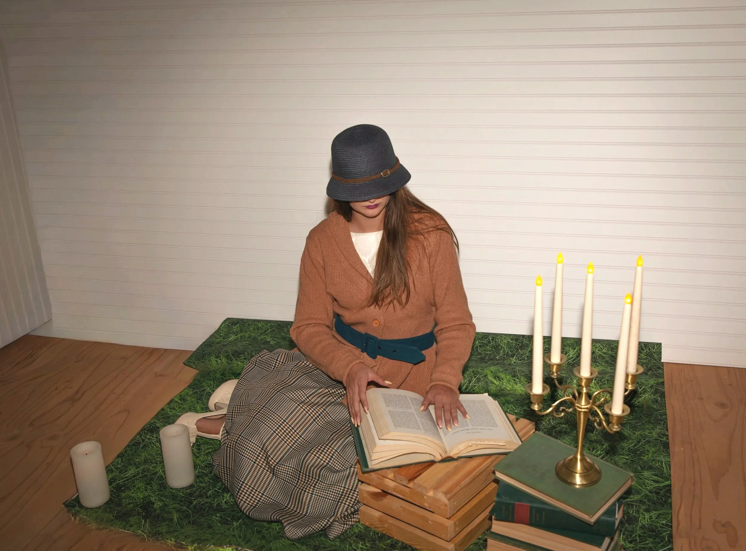 Studio session test for high desert fantasy photographer. Woman sitting on floor with books and candelabra, wearing vintage clothing.