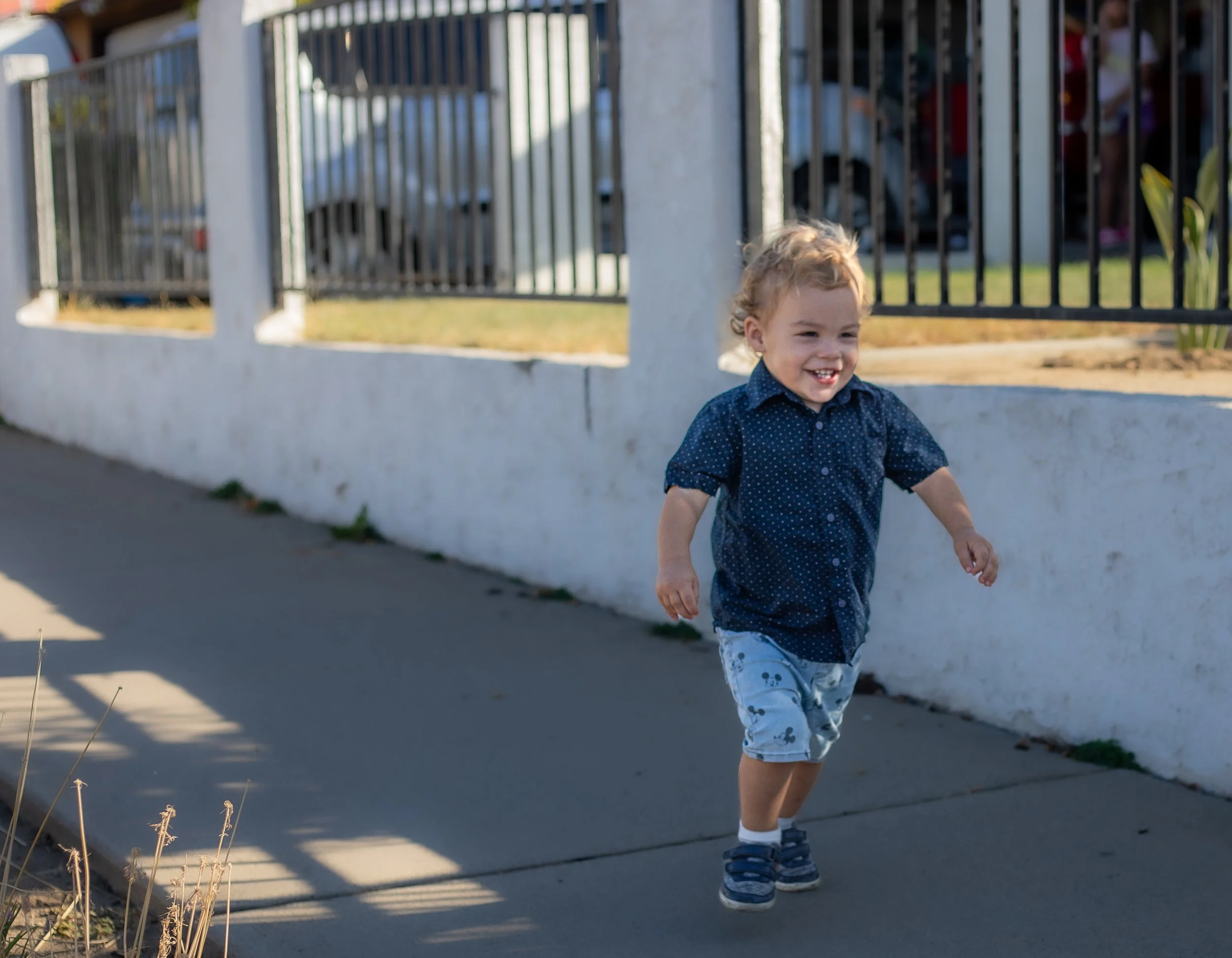 Toddler running on sidewalk, laughing, by Hesperia family photographer.