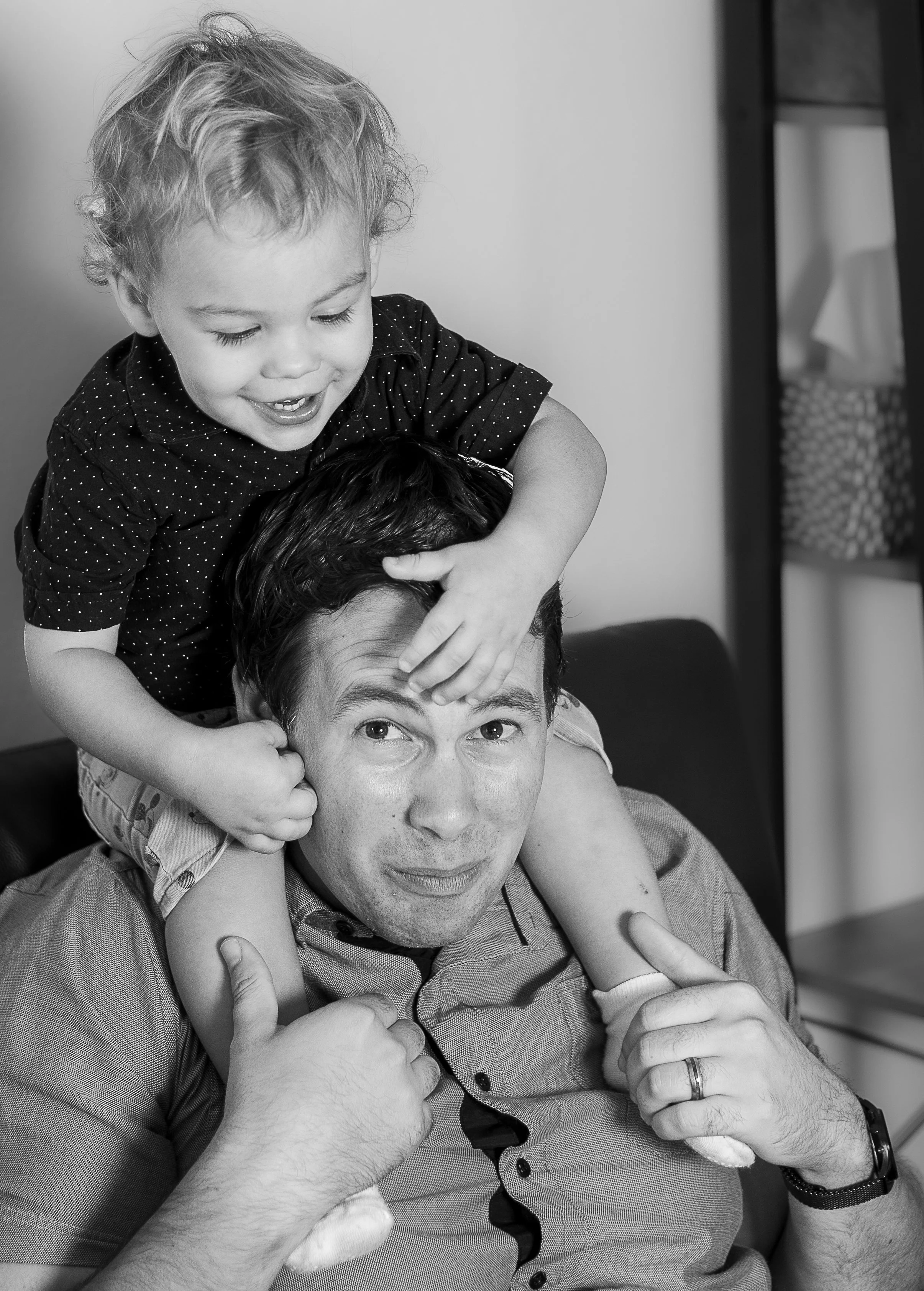 son sitting on dads shoulders playing with his hair