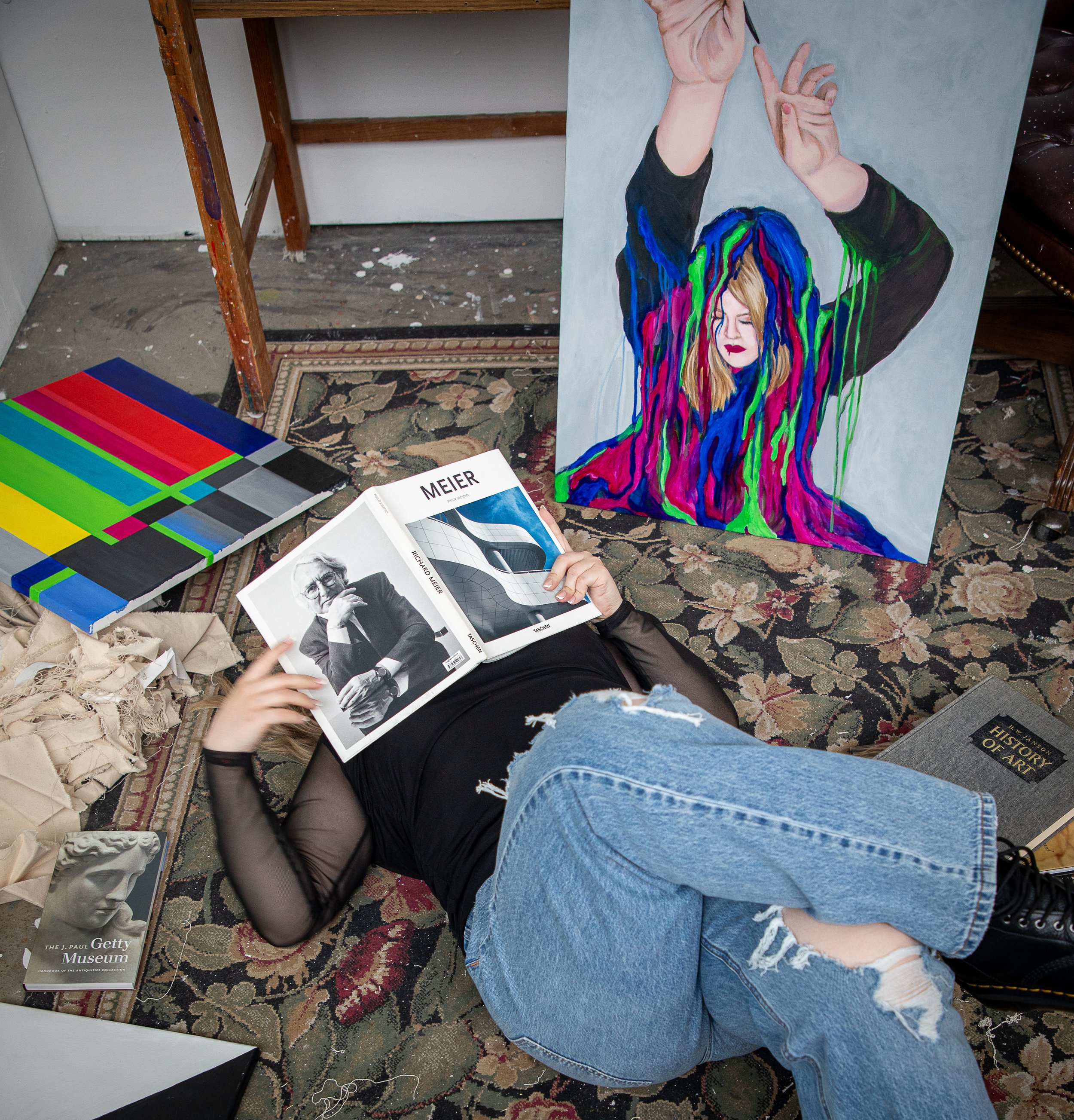 Woman laying under book in art studio. College graduate fantasy photography in wrightwood, ca.