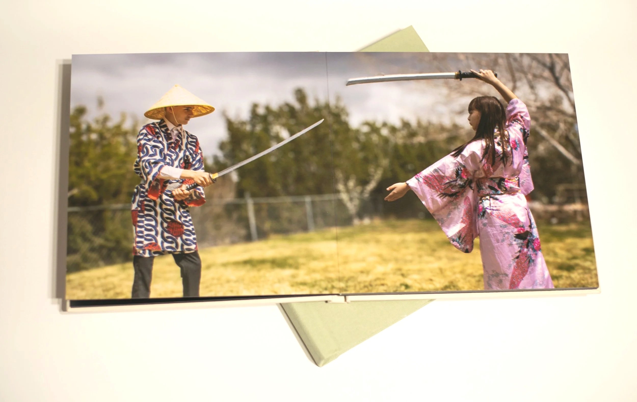 Image of 2 kids dressed in japanese robes play fighting with swords, in an album by fantasy photographer, Annette Marie in southern california.