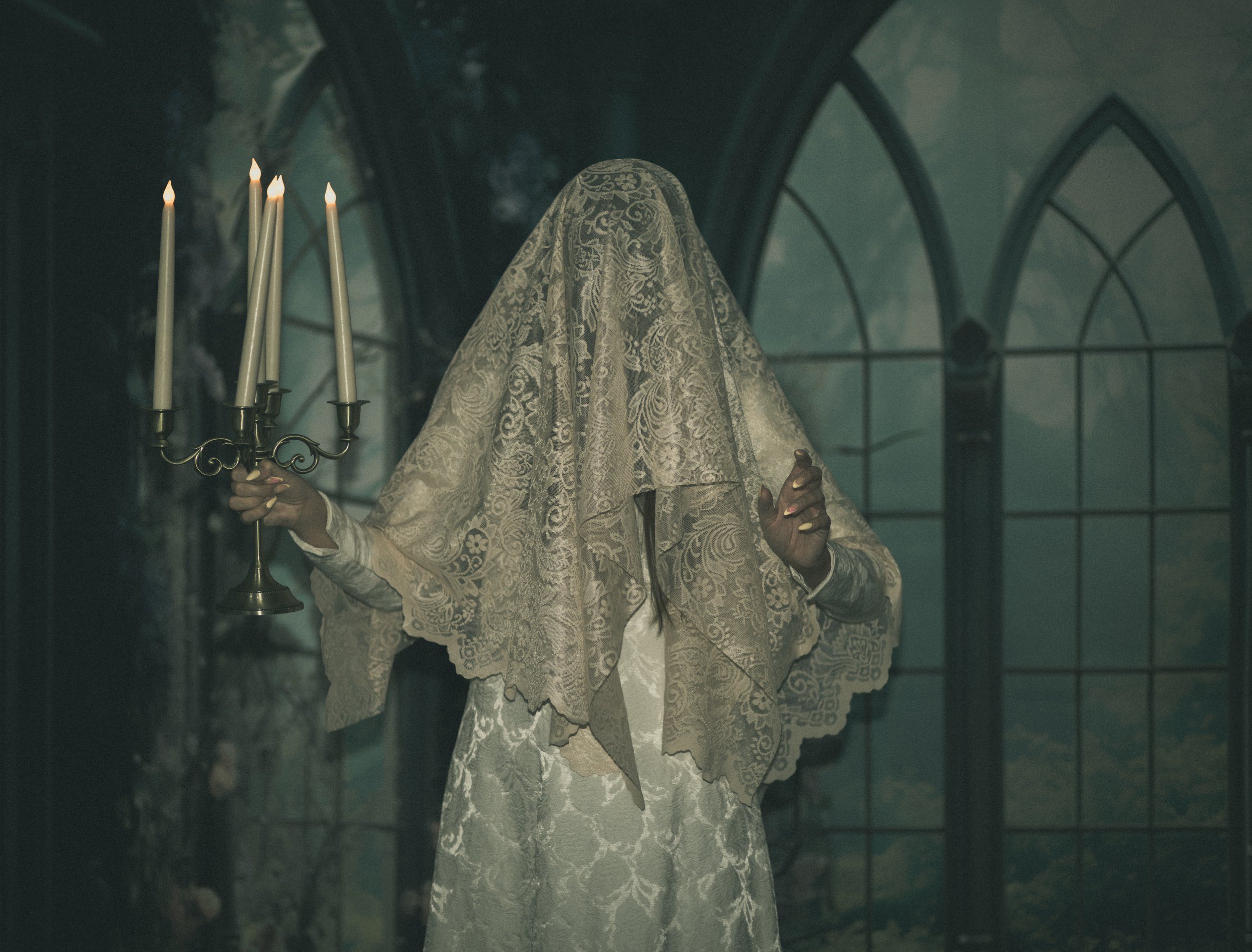 halloween spooky woman dressed as dead bride with lace veil holding candelabra walking through castle at night. Fantasy fine art photographer, annette marie serves the high desert and inland empire of southern california.