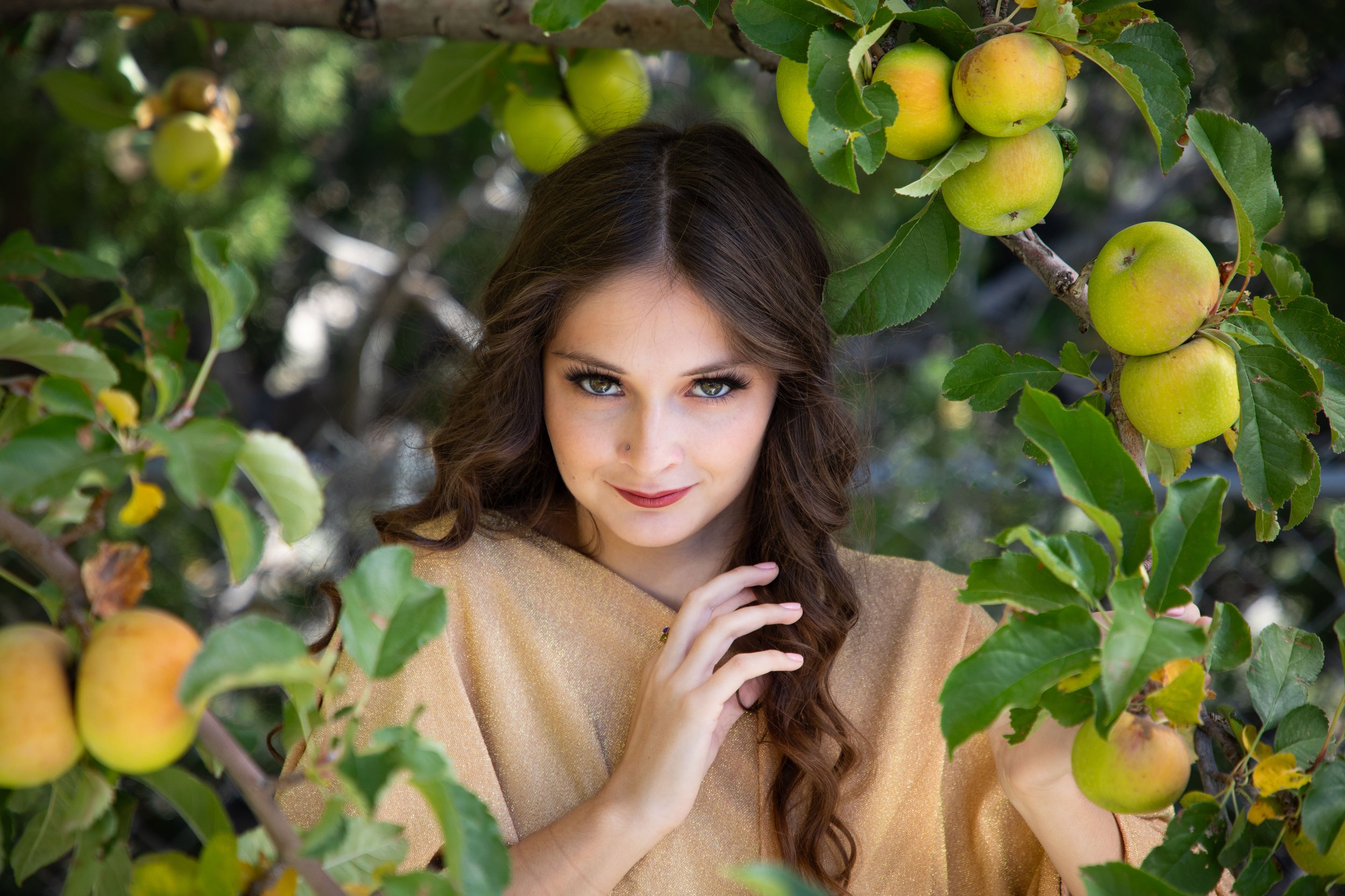 Woman dressed in yellow looking through an apple tree. Fantasy photographer, annette marie in the high desert, Victorville california.