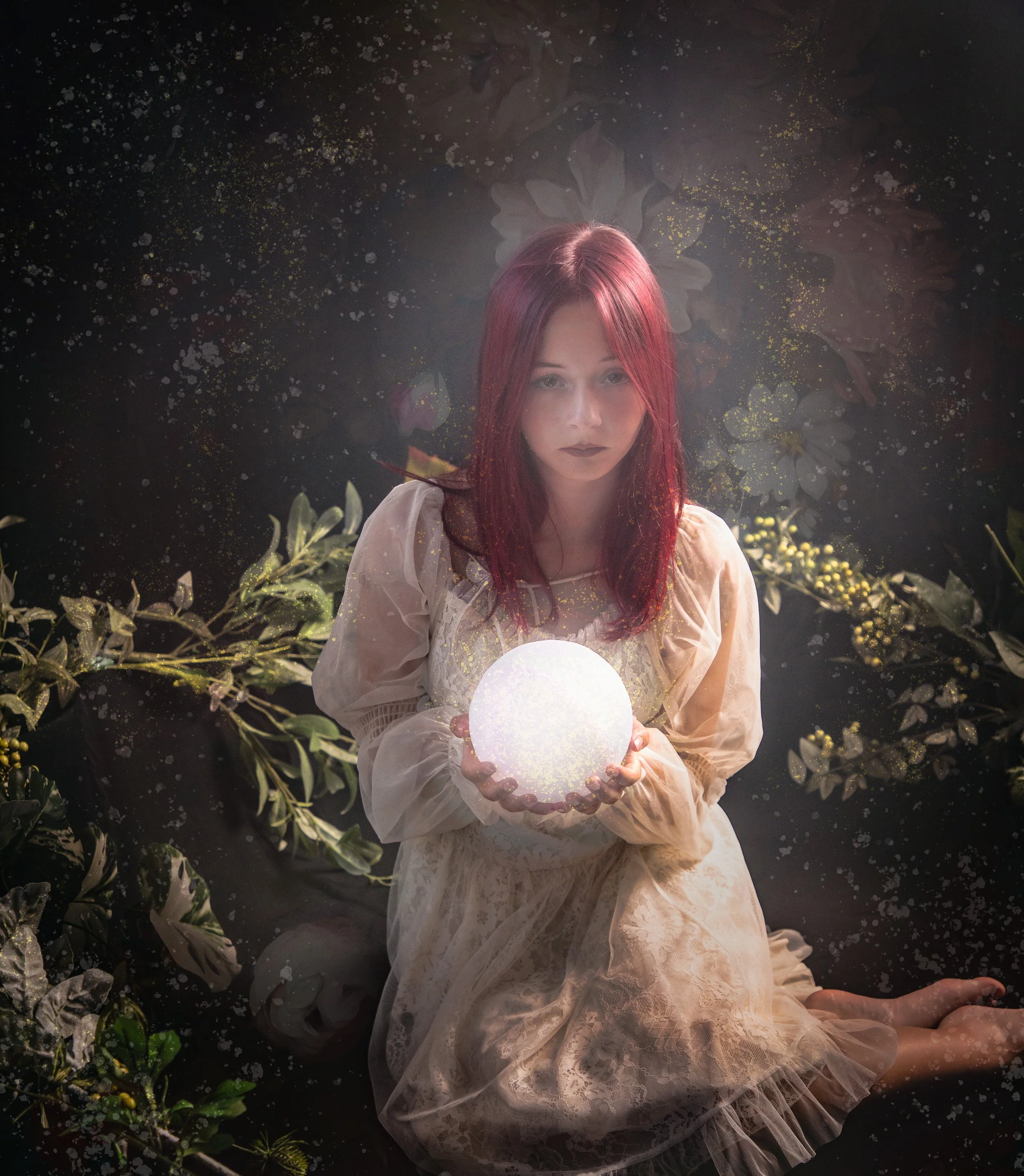 Girl holding a moon light sitting among greenery and flowers. Red hair and a white dress by fantasy photographer in the high desert.