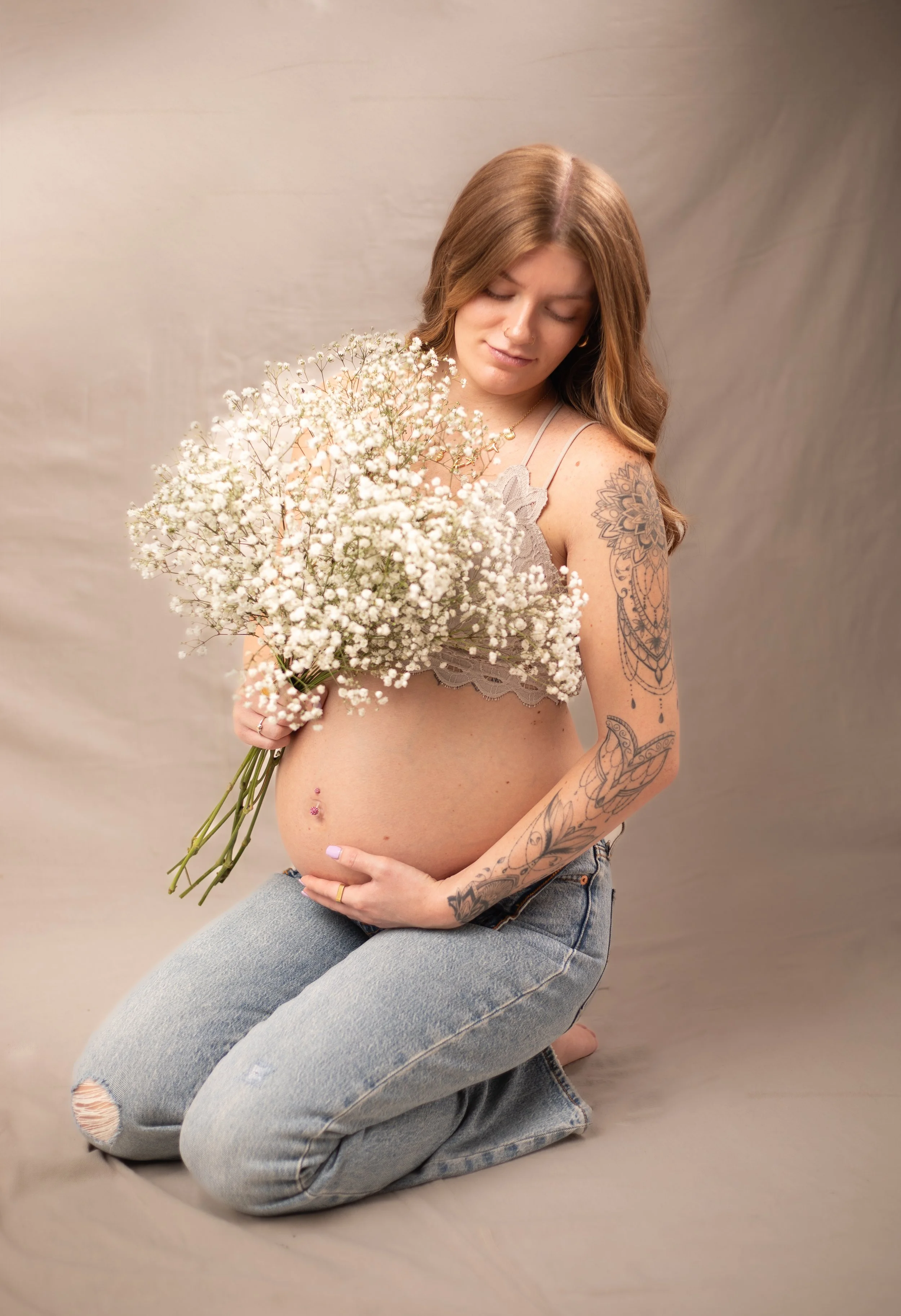 pregnant woman sitting in jeans and holding big bouquet of babys breath. high desert family photographer for maternity.