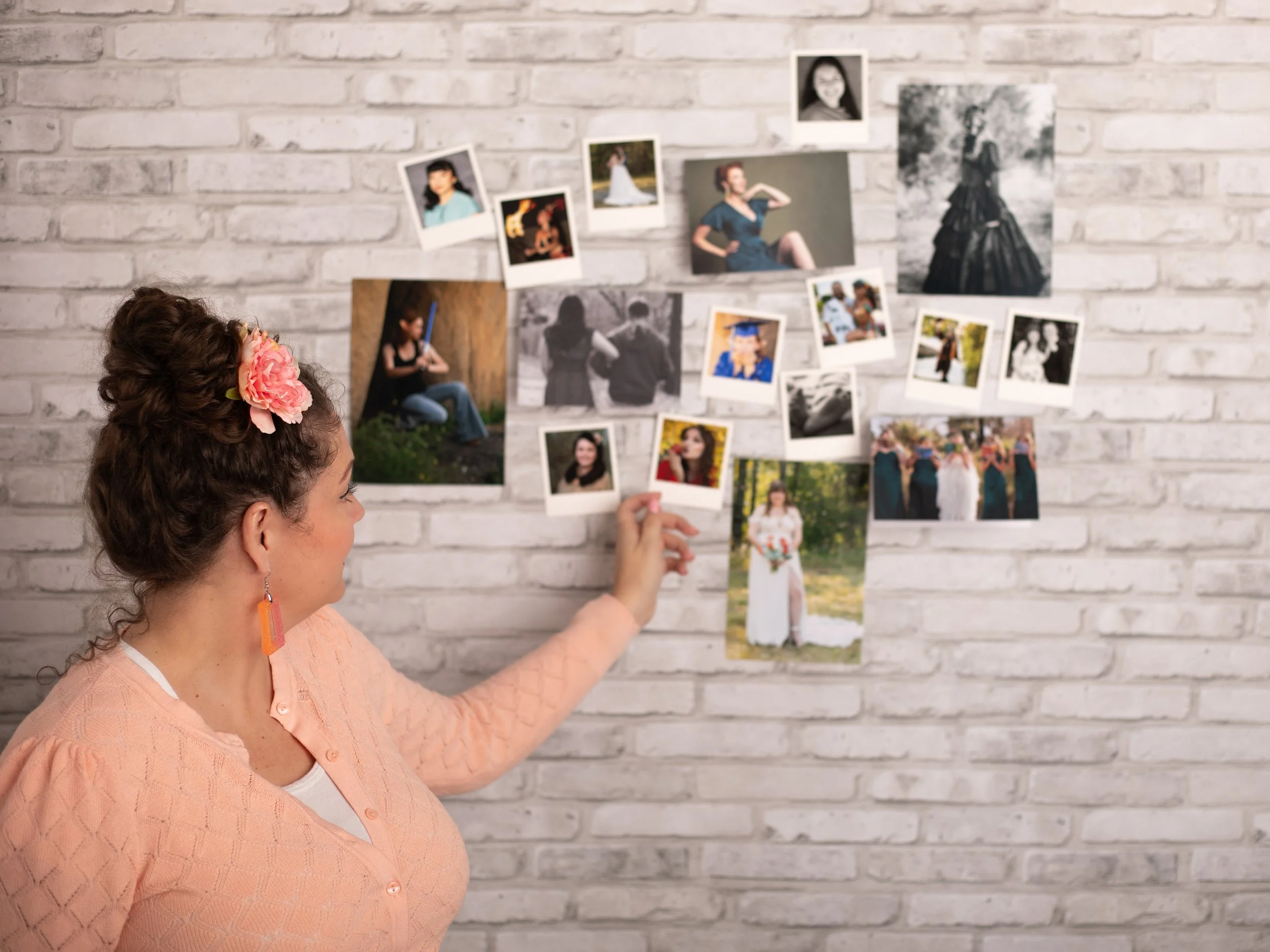Annette Marie photography looking at printed images displayed on a brick wall in her studio. portrait