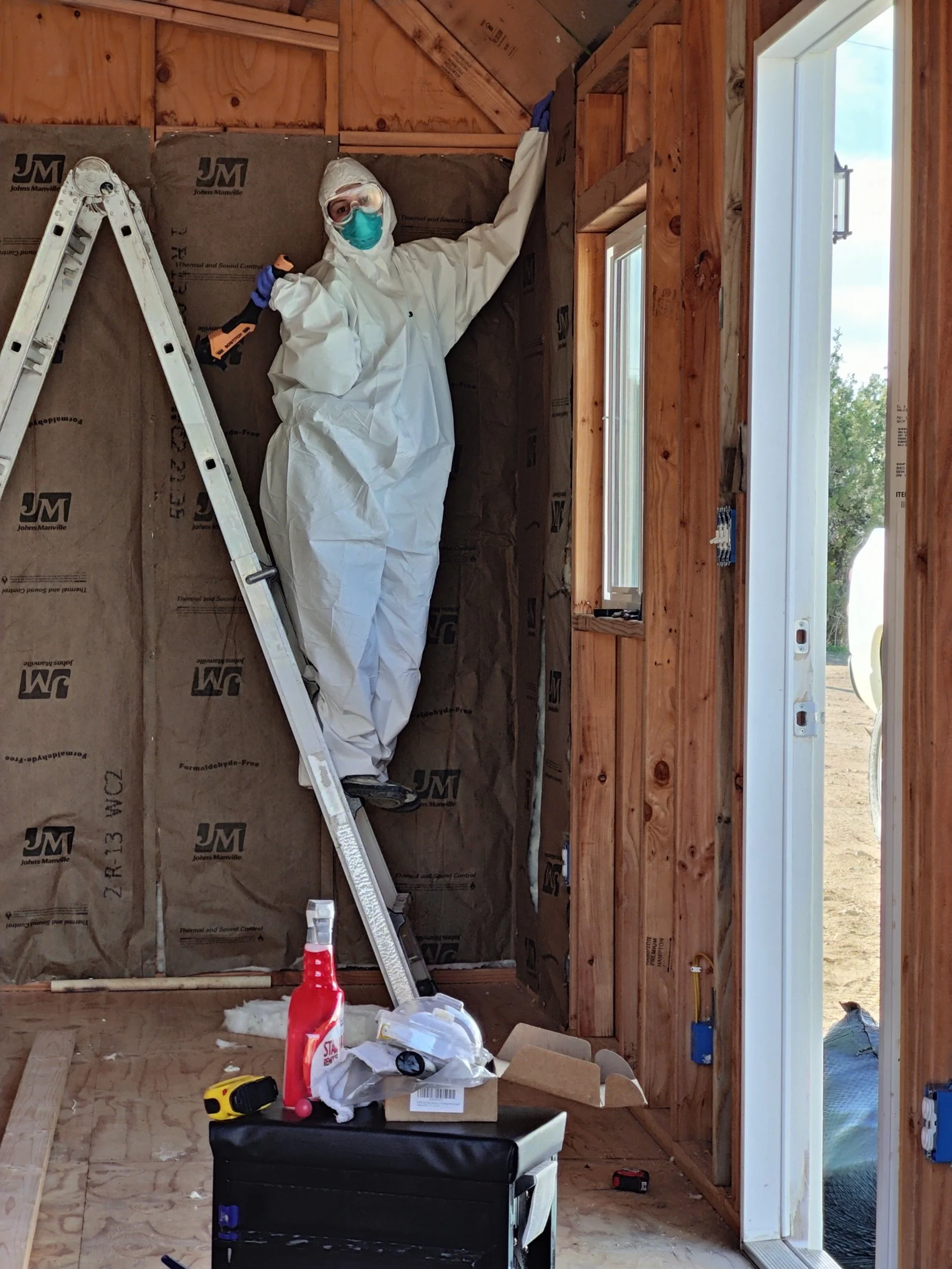 person wearing suit for installing insulation into shed. DIY shed to portrait studio.