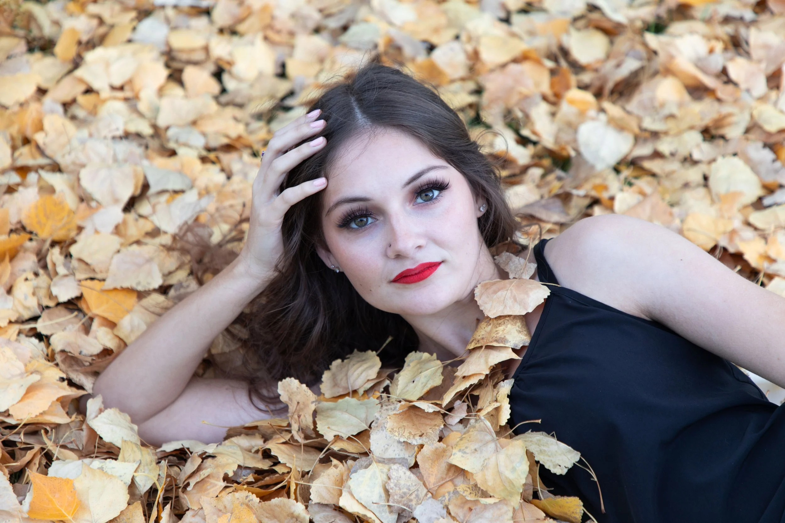 Woman laying in the fall leaves with red lips by fantasy photographer, Annette Marie in the high desert.