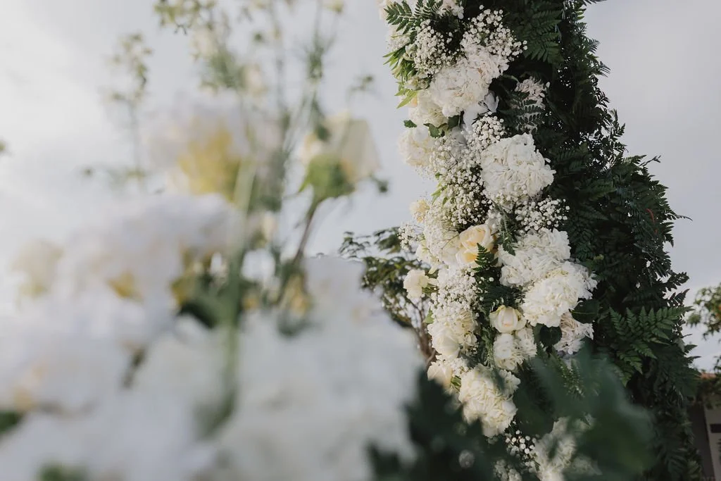 White floral arrangement with green leaves, likely part of a wedding or special event decoration.