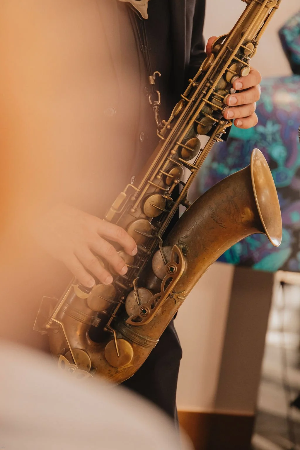 Close-up of a person playing a brass saxophone, focusing on their hands and the instrument.