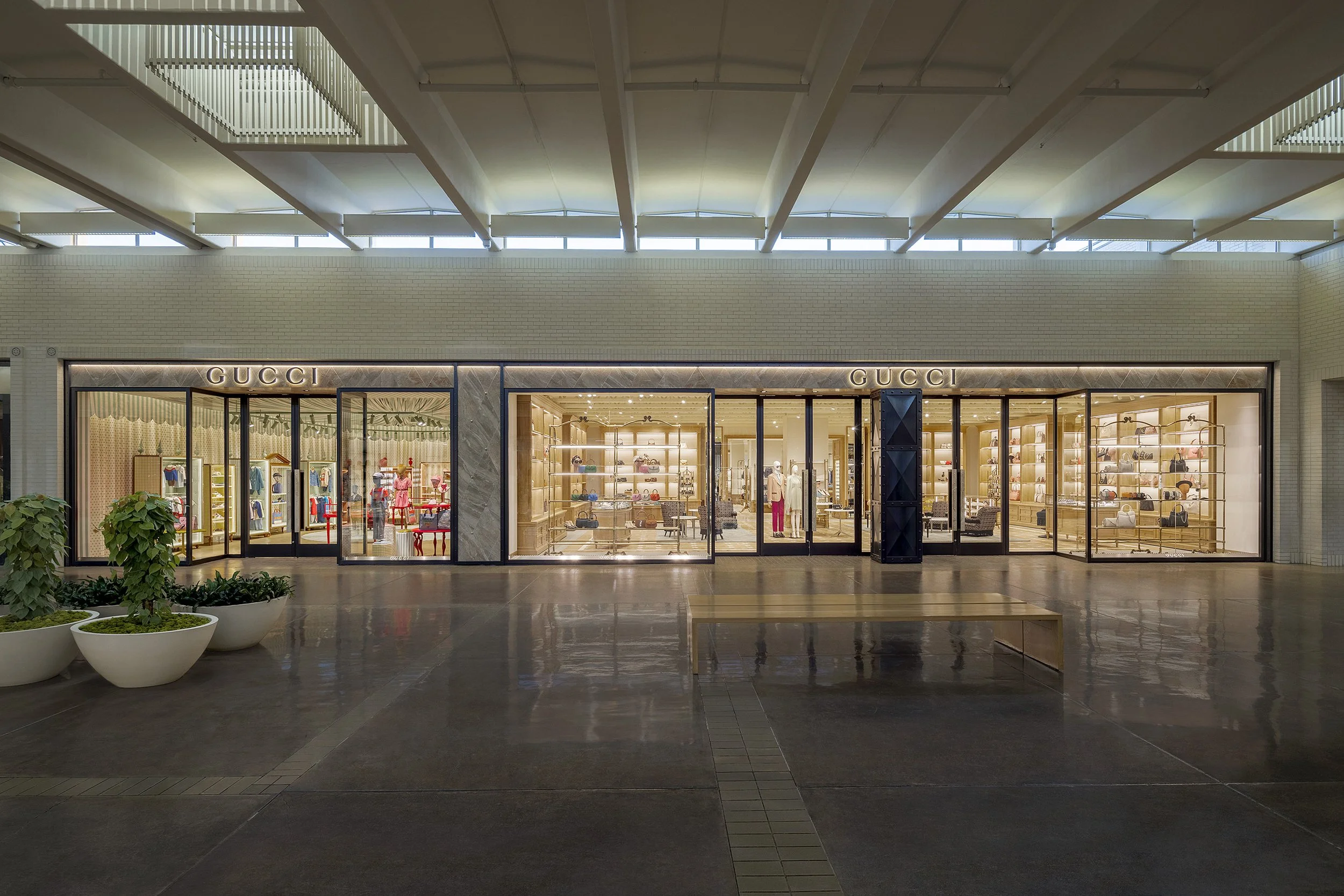 Indoor view of a Gucci store in a mall, featuring large glass windows, stylish interiors, and modern architectural elements.