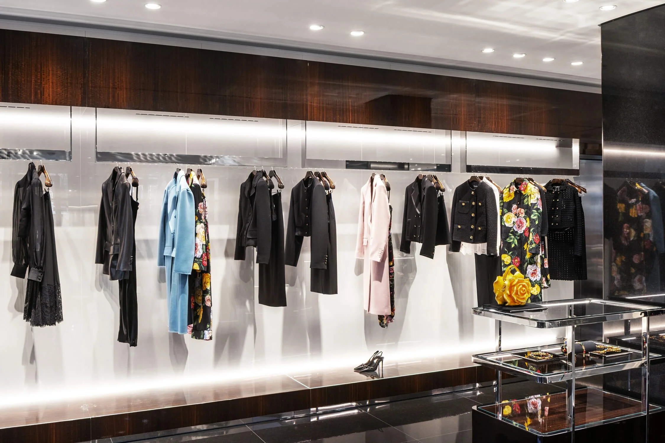 Women’s luxury coats and floral jackets displayed on wall-mounted racks inside Dolce & Gabbana store
.