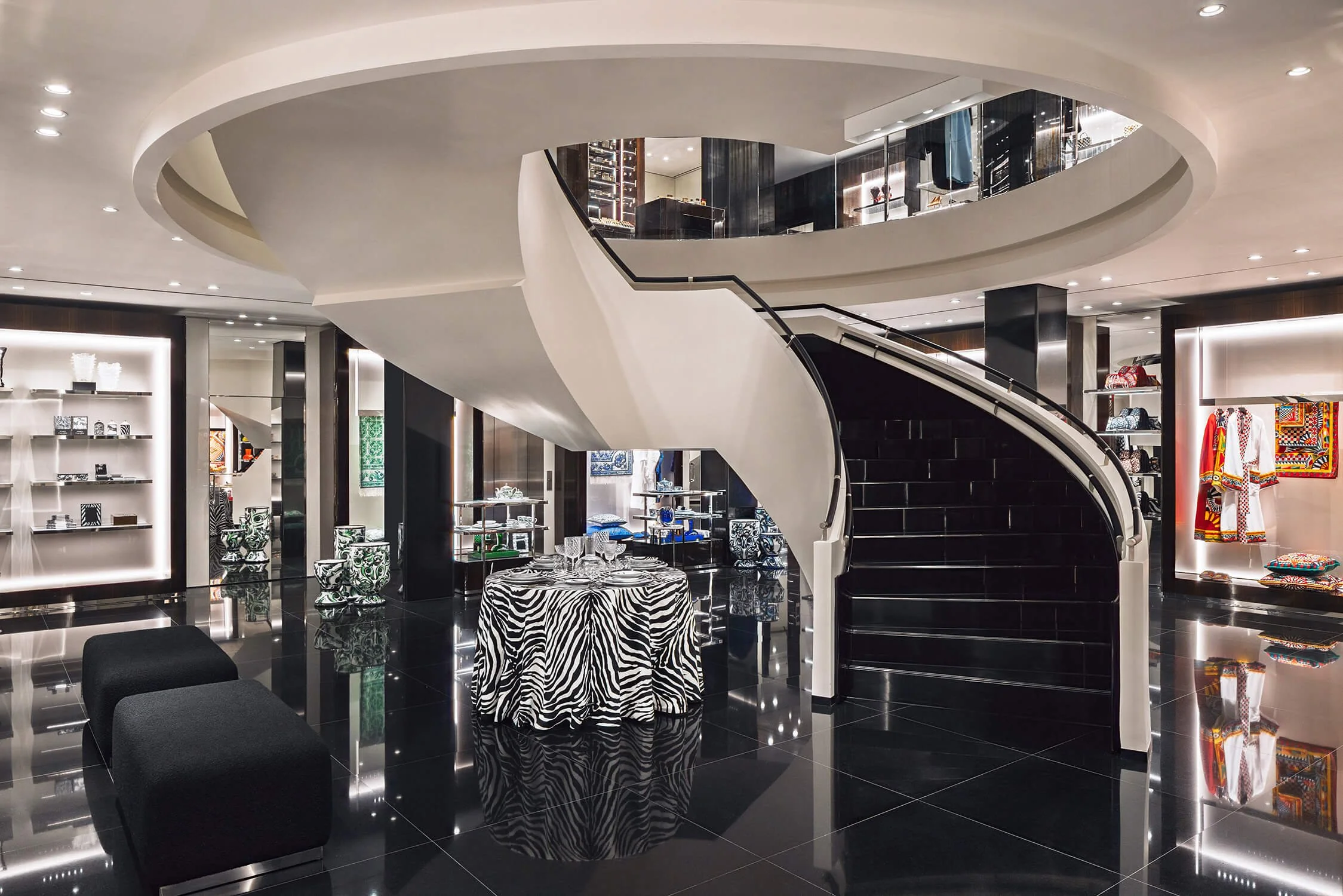 Spiral staircase in Dolce & Gabbana store surrounded by designer displays and zebra-patterned table
