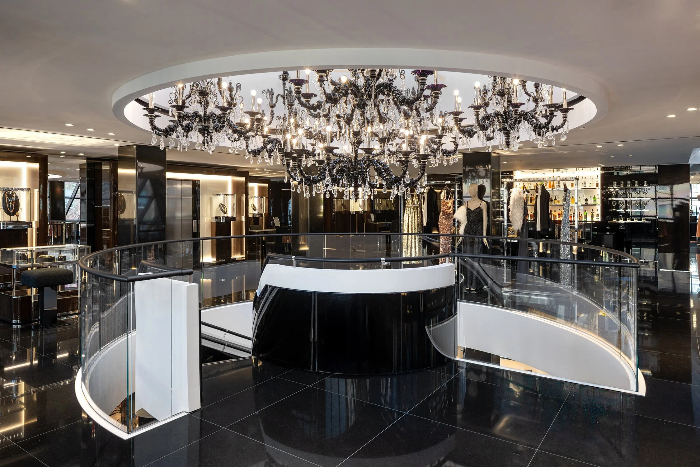 Luxurious chandelier above spiral staircase in Dolce & Gabbana store with eveningwear on mannequins
