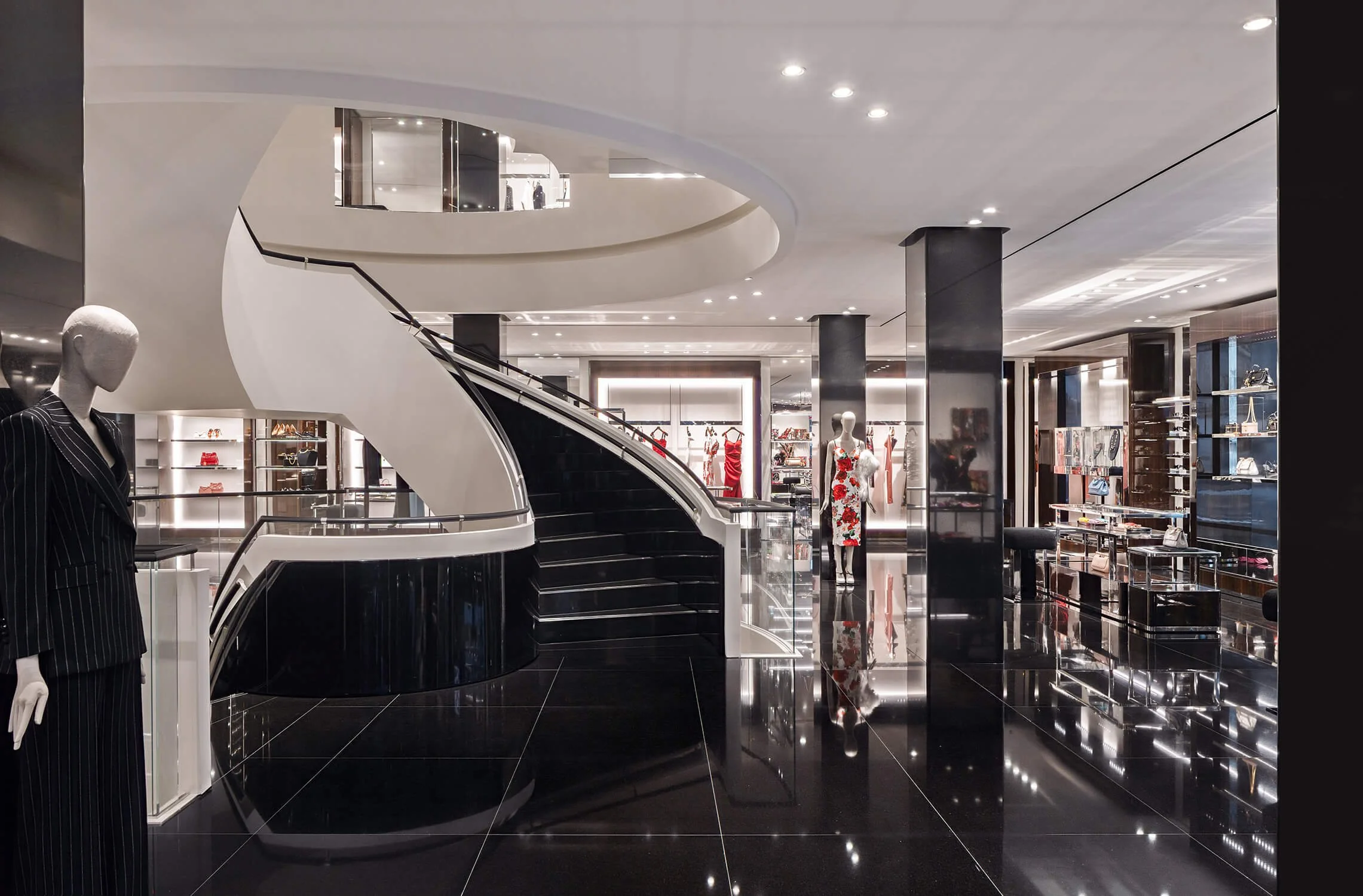 Interior of Dolce & Gabbana store featuring modern black staircase and mannequins in designer fashion