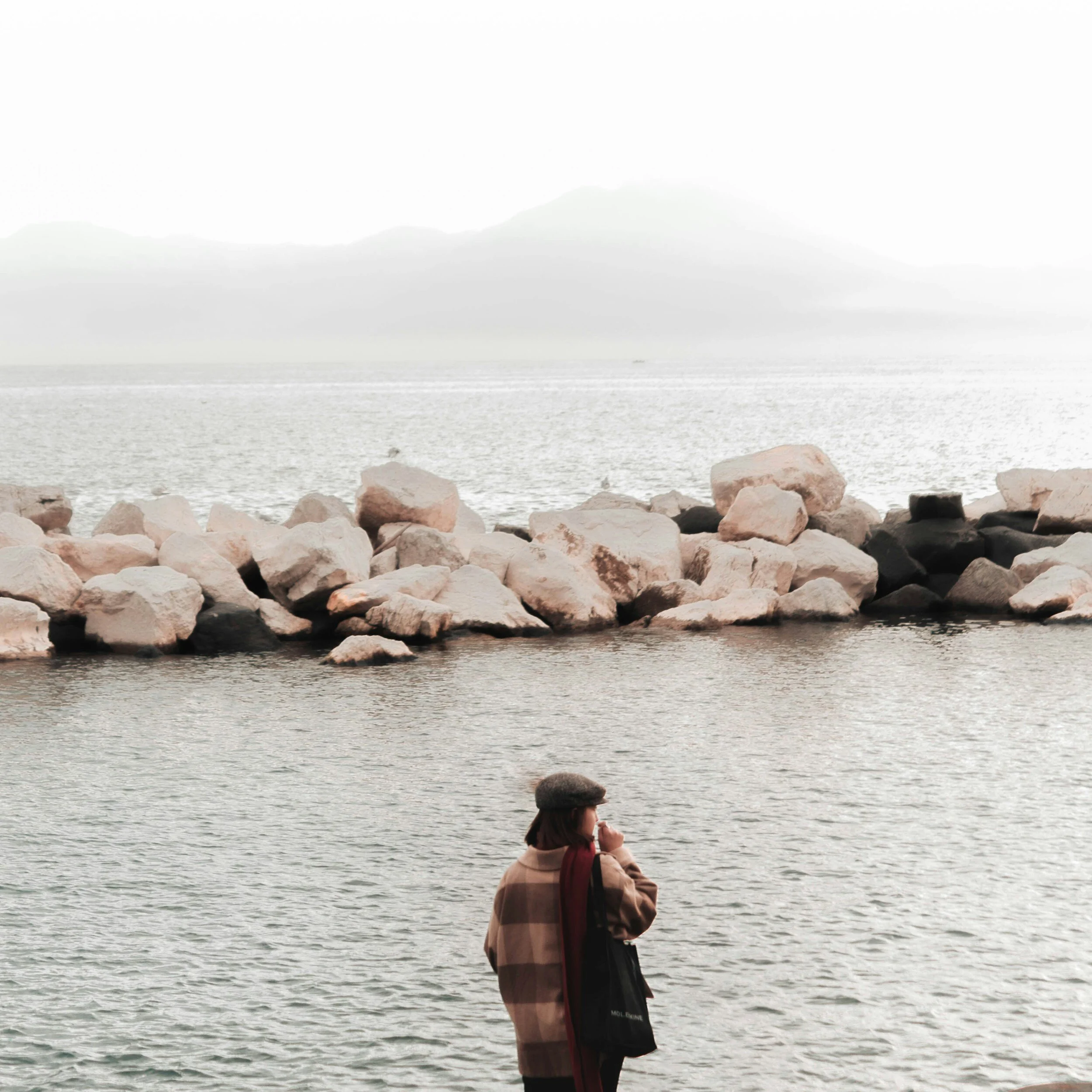 Woman looking out over water and rocks, reflecting depth and emotional sensitivity