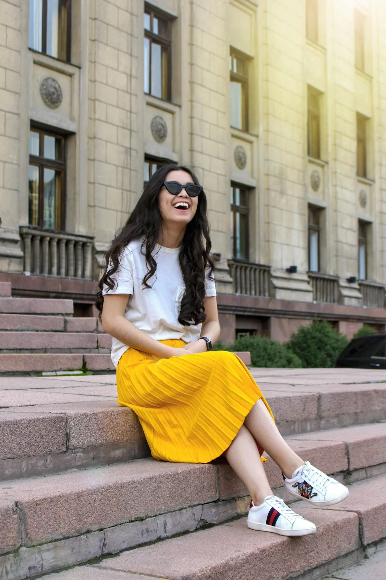 Smiling Asian woman in a yellow skirt looking up toward the sun, expressing joy, freedom, and cultural confidence