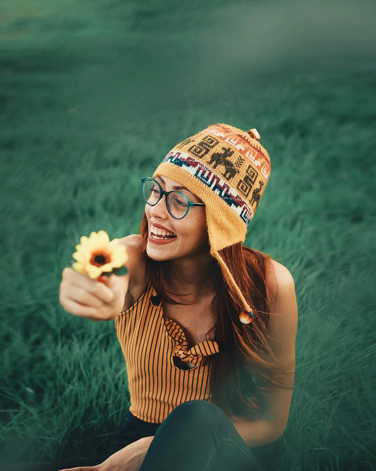 Smiling woman holding a yellow daisy, expressing joy and embracing sensitivity