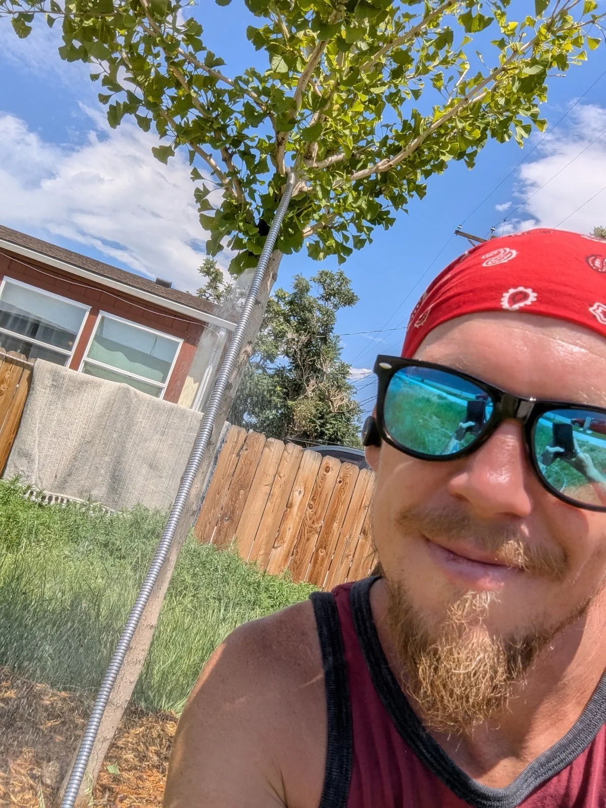 man in sunglasses smiling by tree